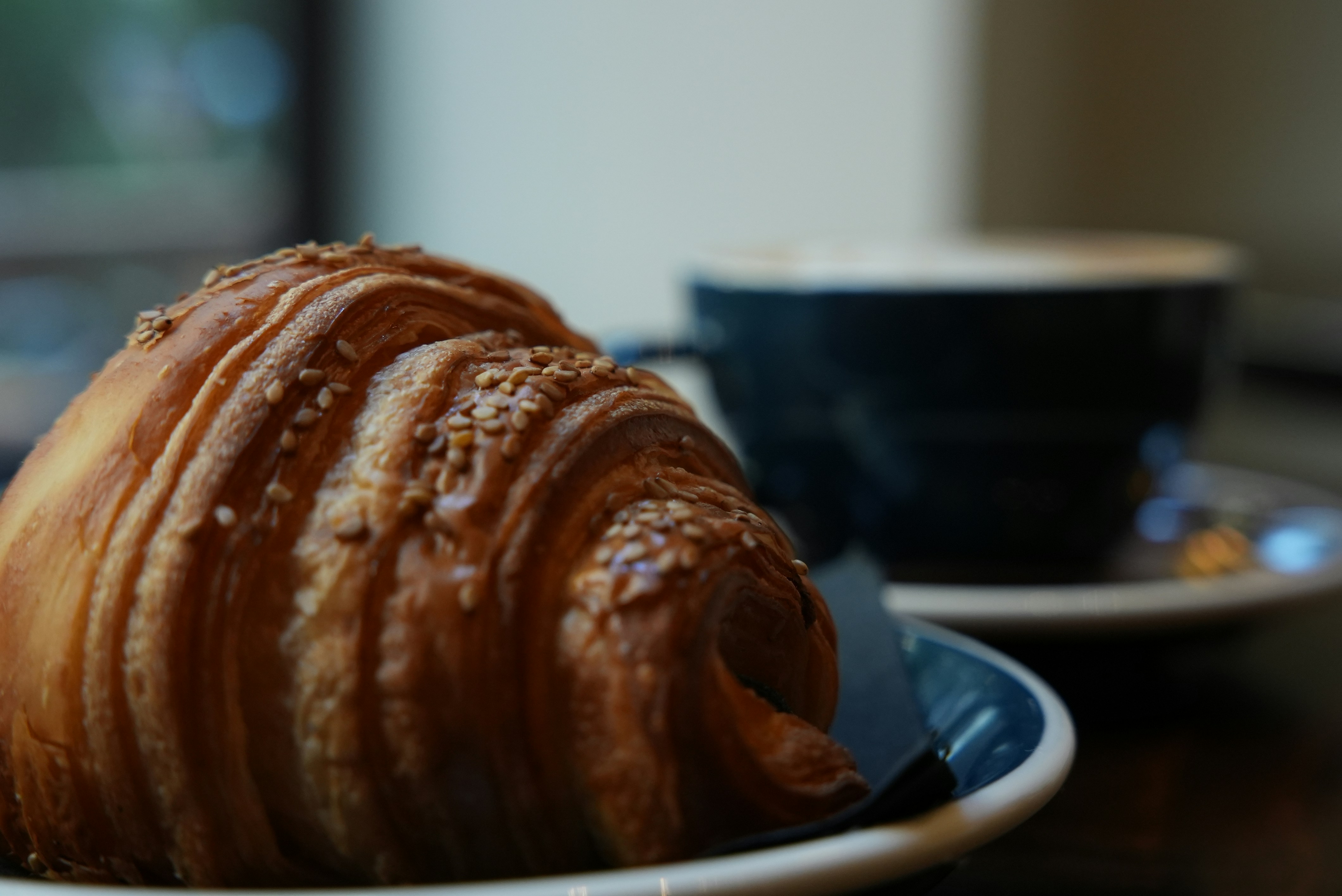 Un cruasán y una taza de café sobre una mesa.