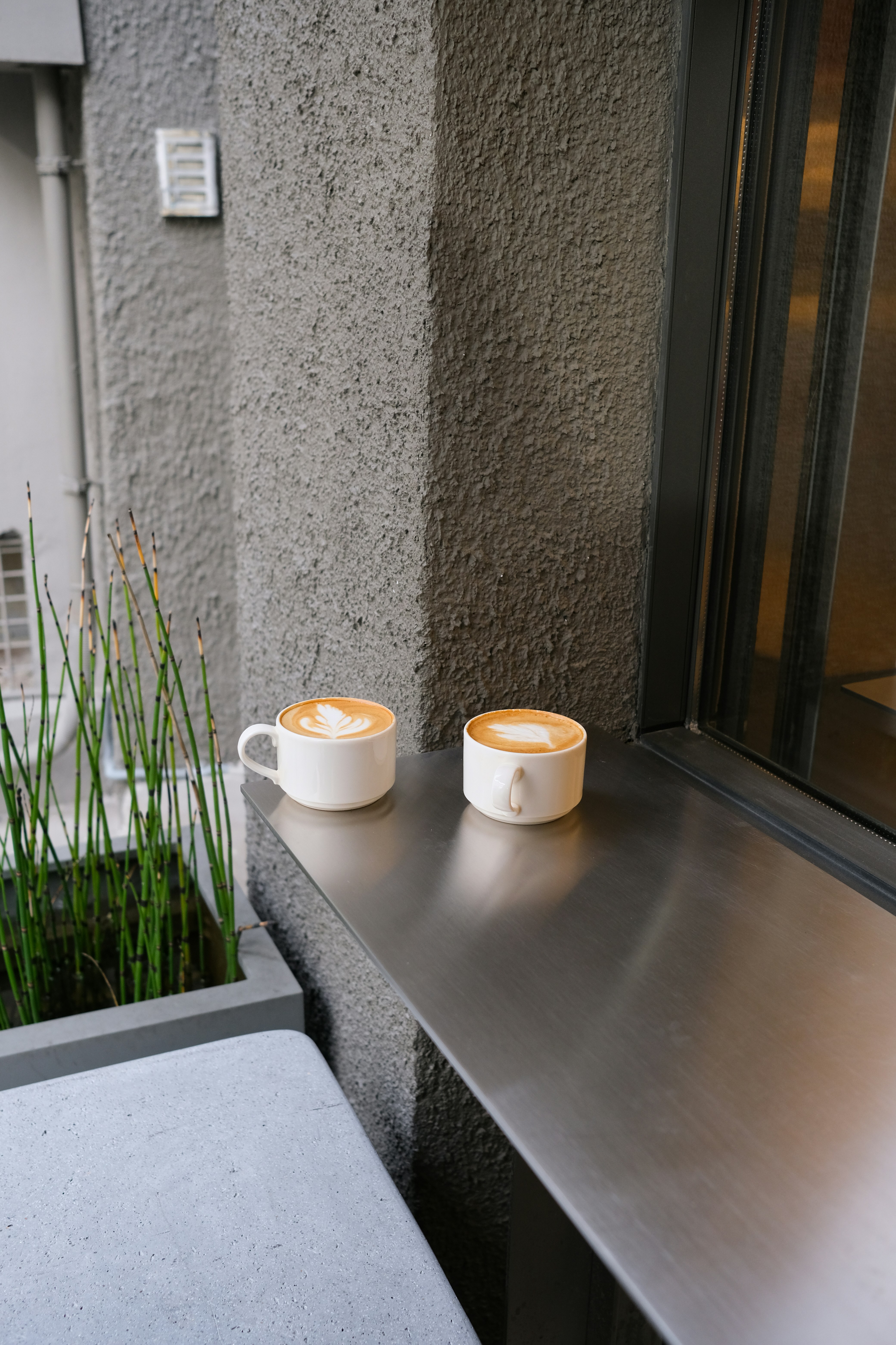 Two cups of coffee with latte art on a ledge.