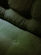 Close-up of green corduroy fabric with tufted buttons.