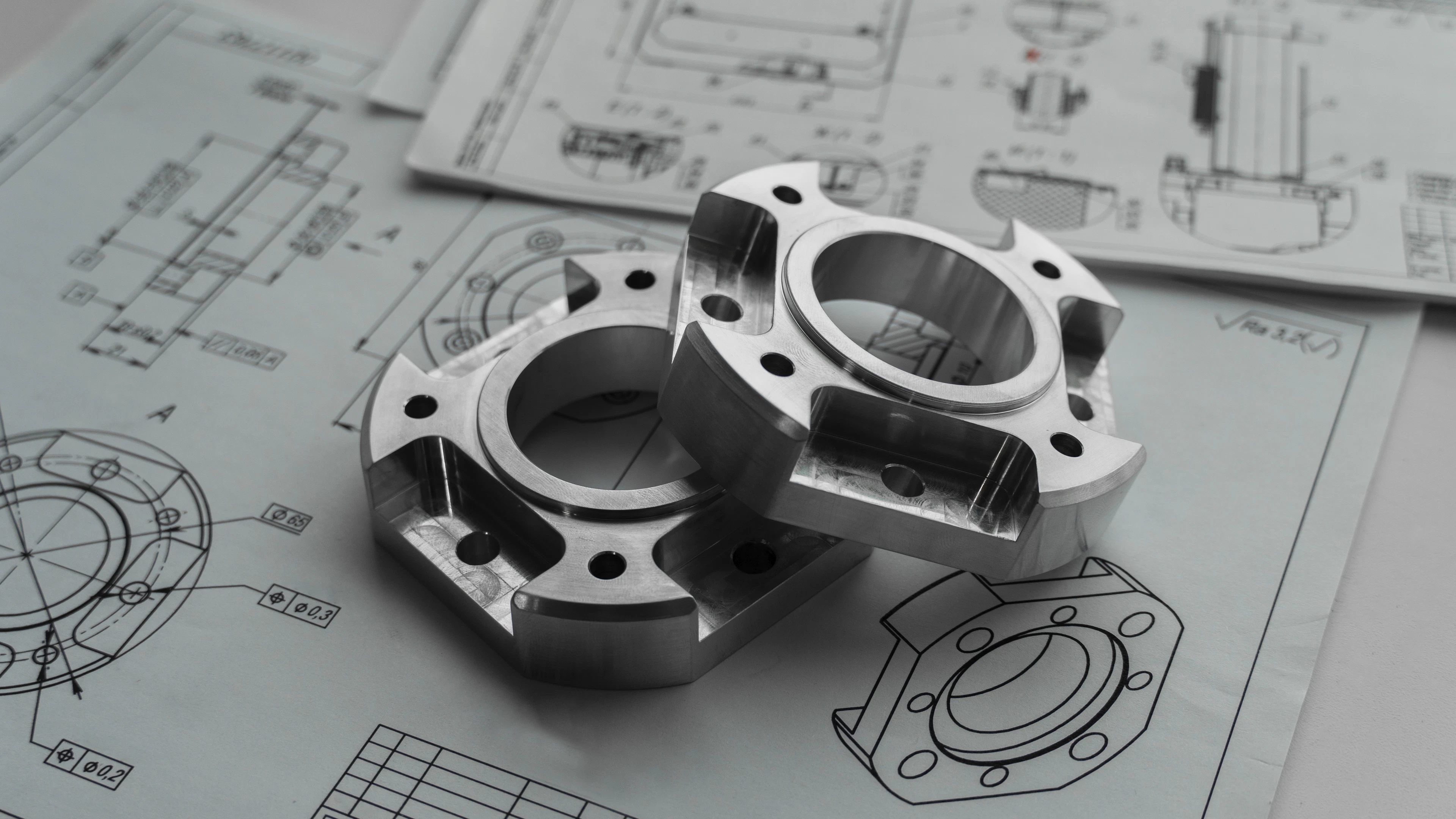 Two machined parts resting on engineering drawings