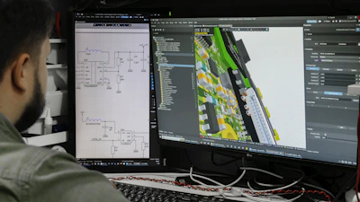 Man looking at circuit board design on computer screen.