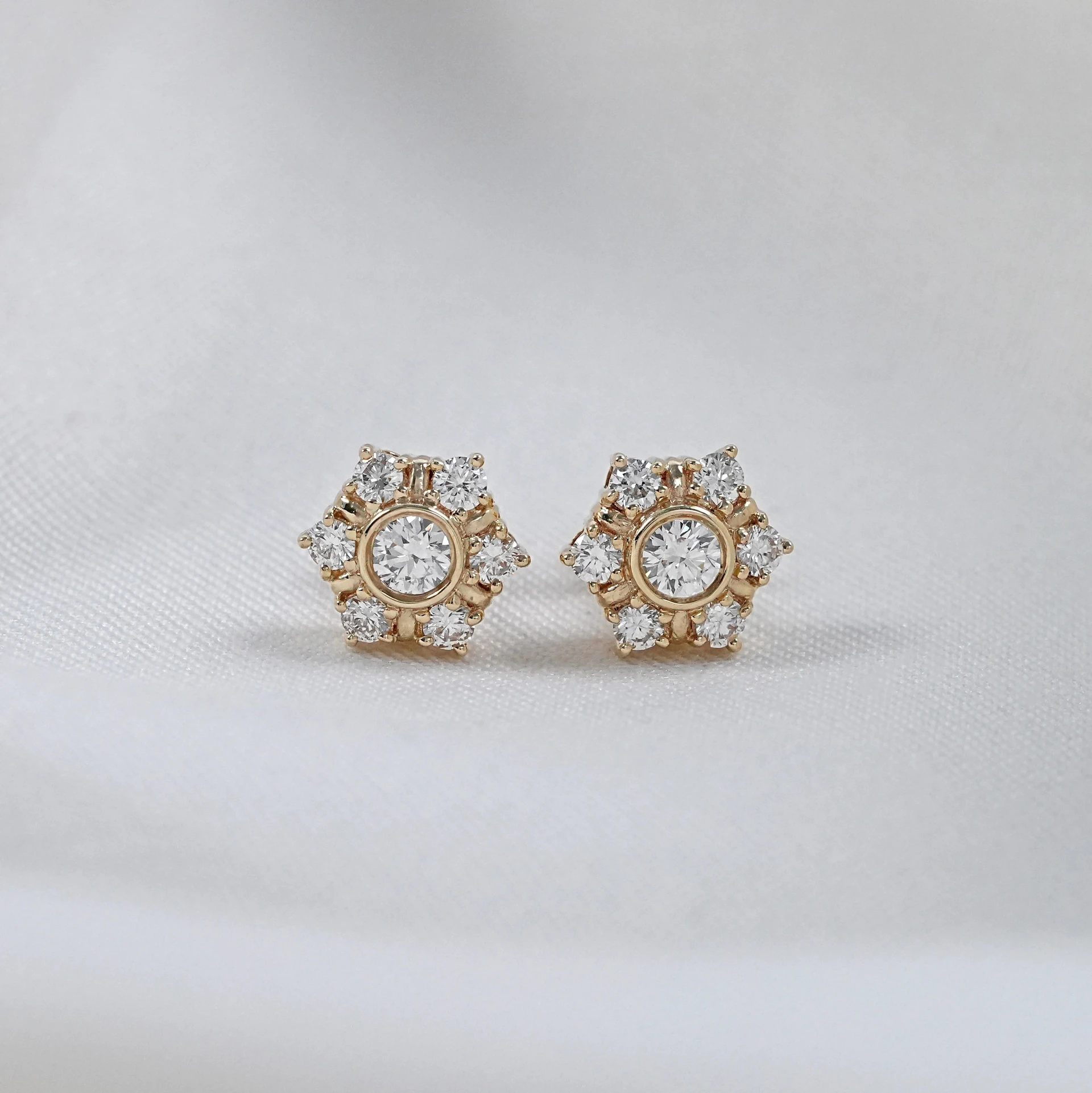 Delicate hexagonal diamond stud earrings on white background