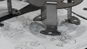 Metal components resting on engineering blueprints.