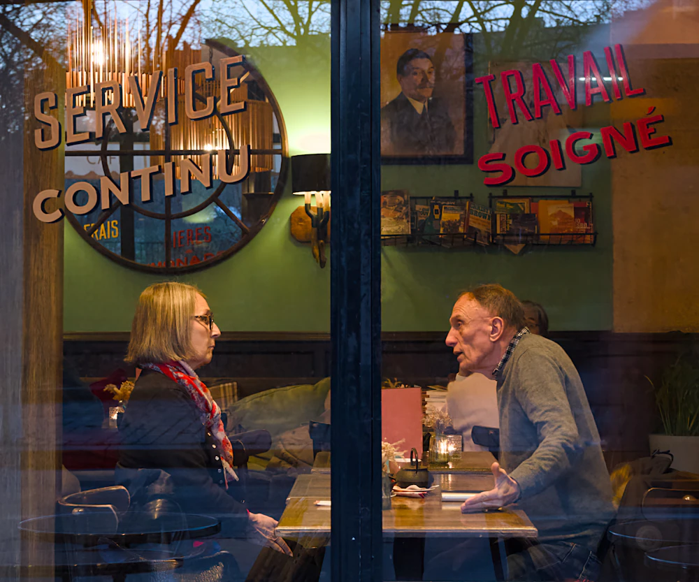 Zwei Personen sprechen an einem Tisch in einem Café