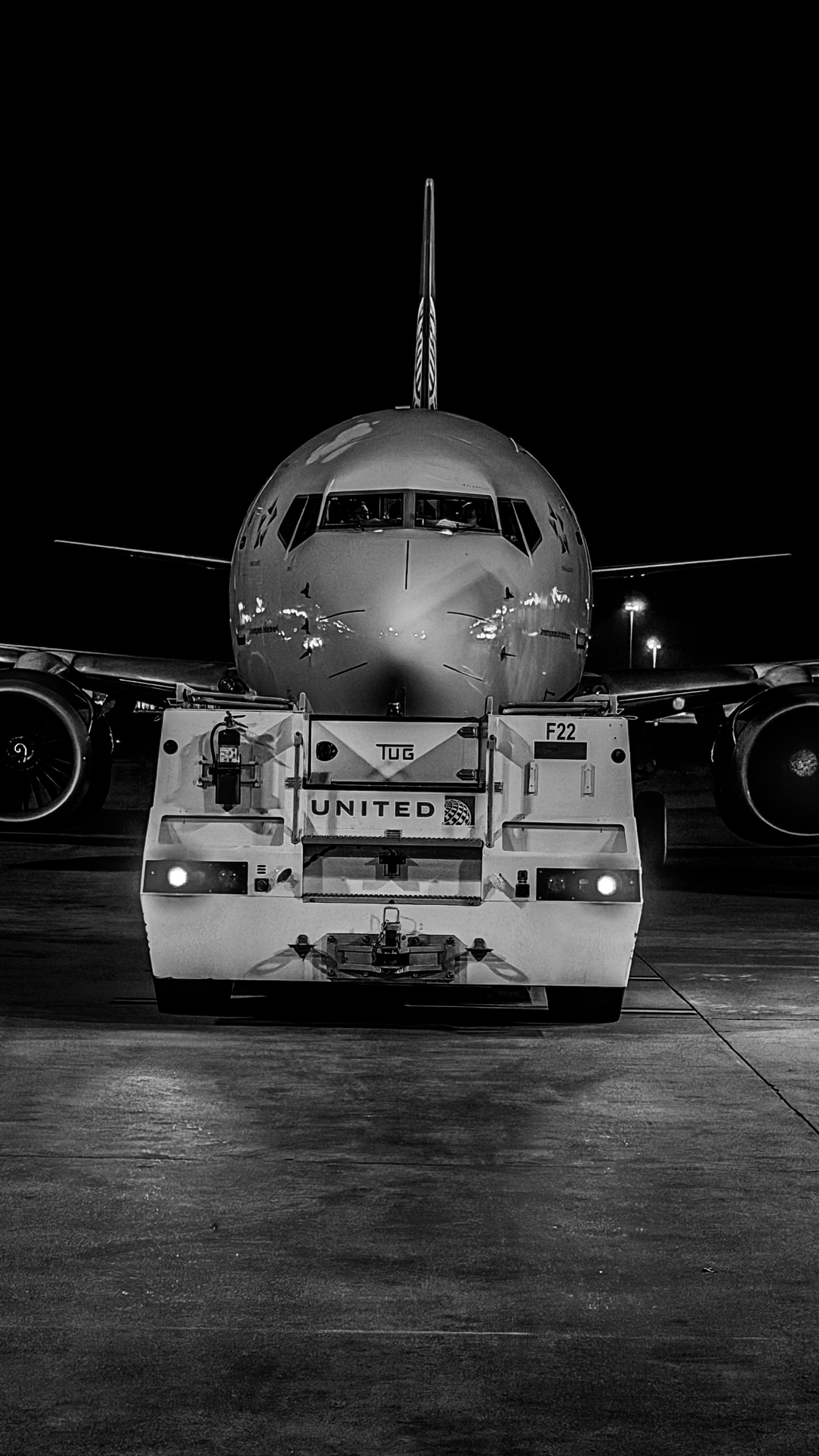Avião sendo rebocado à noite no pátio