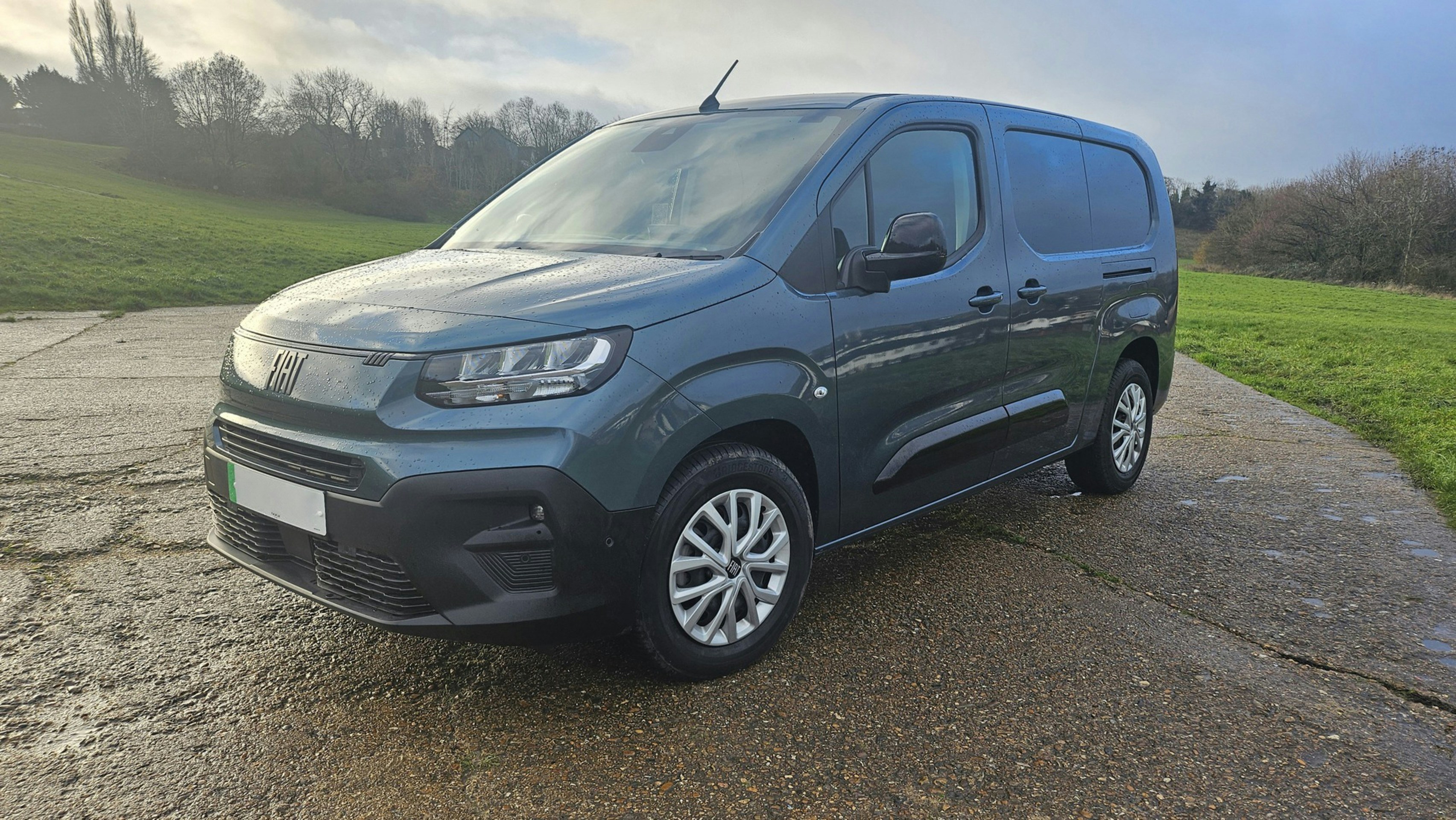 A dark blue panel van parked on a wet road.