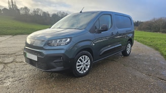 A dark blue panel van parked on a wet road.