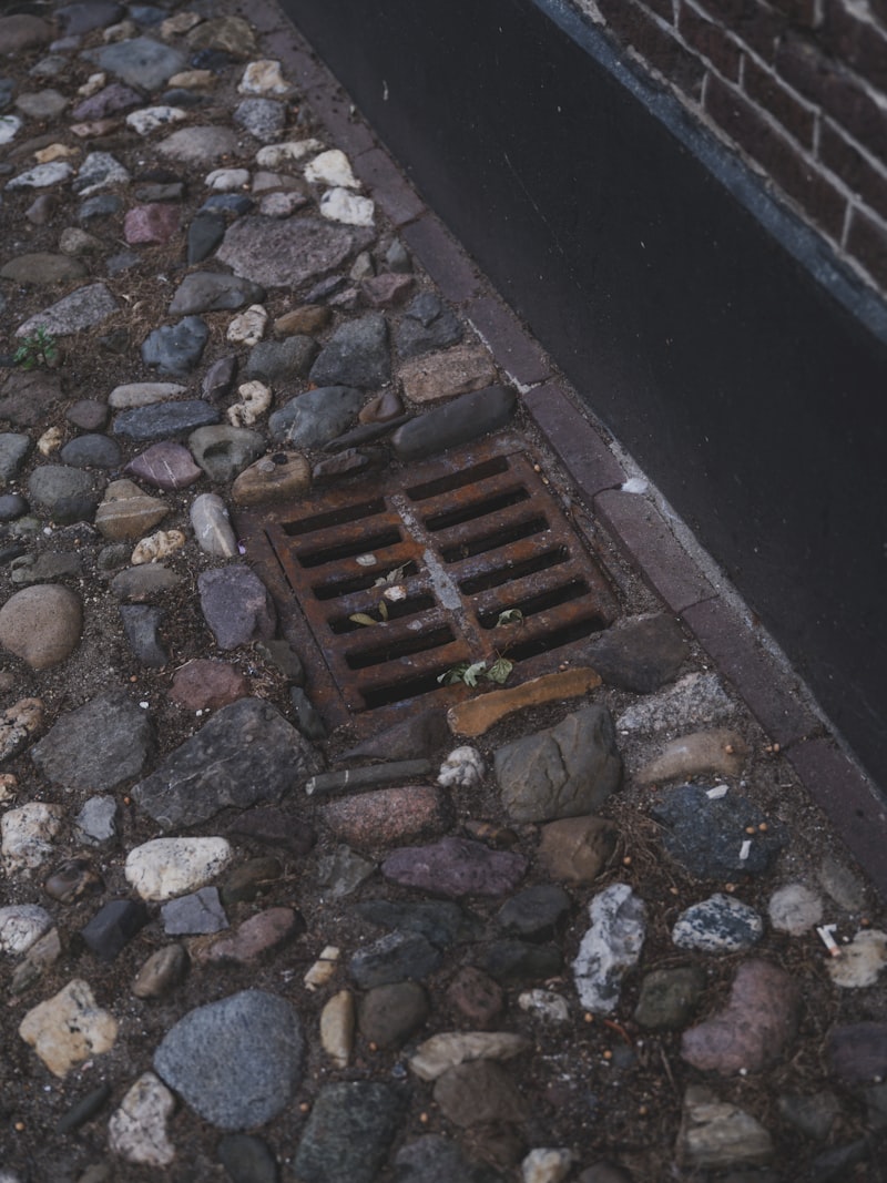 Rostiges Abflussgitter auf Kopfsteinpflaster