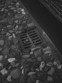 Cobblestone street with a metal grate and brick drain.