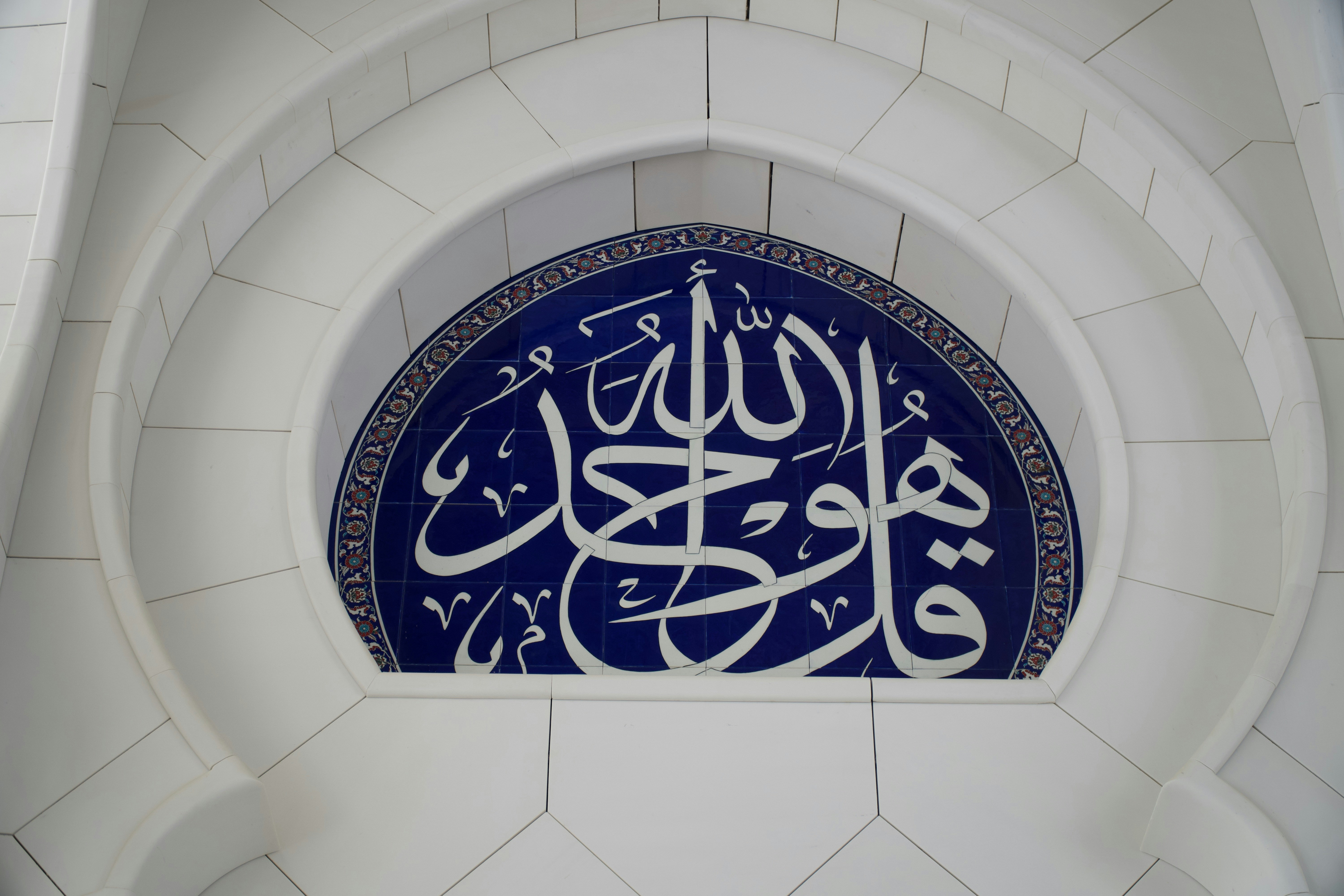 Intricate arabic calligraphy on a blue tiled archway