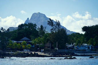 Mountain peak towering over a coastal village and lush trees.