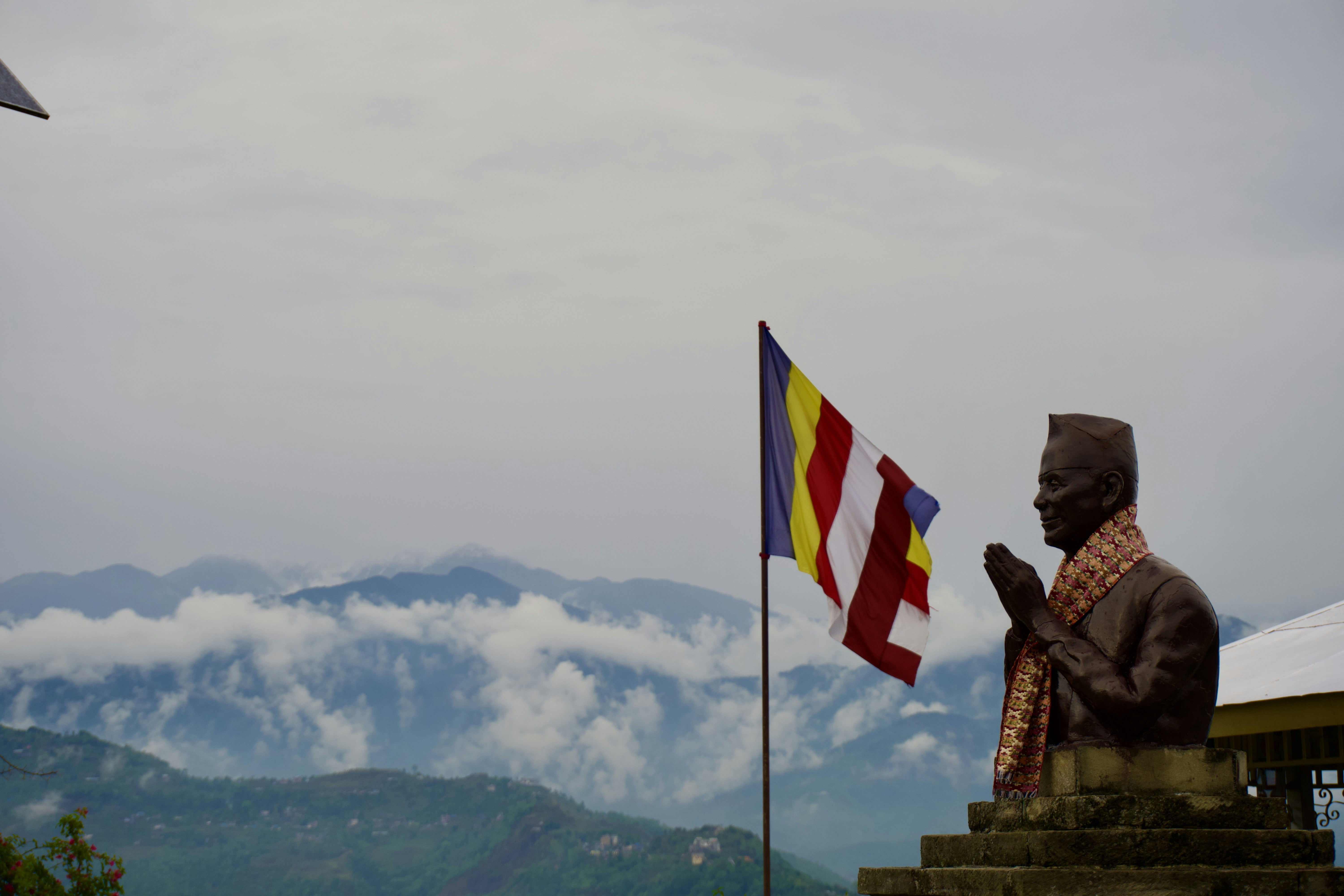 Statua e bandiera con montagne nebbiose sullo sfondo