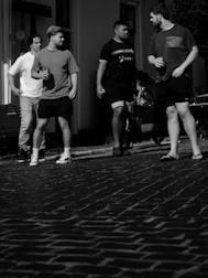 Four men standing on a cobblestone street