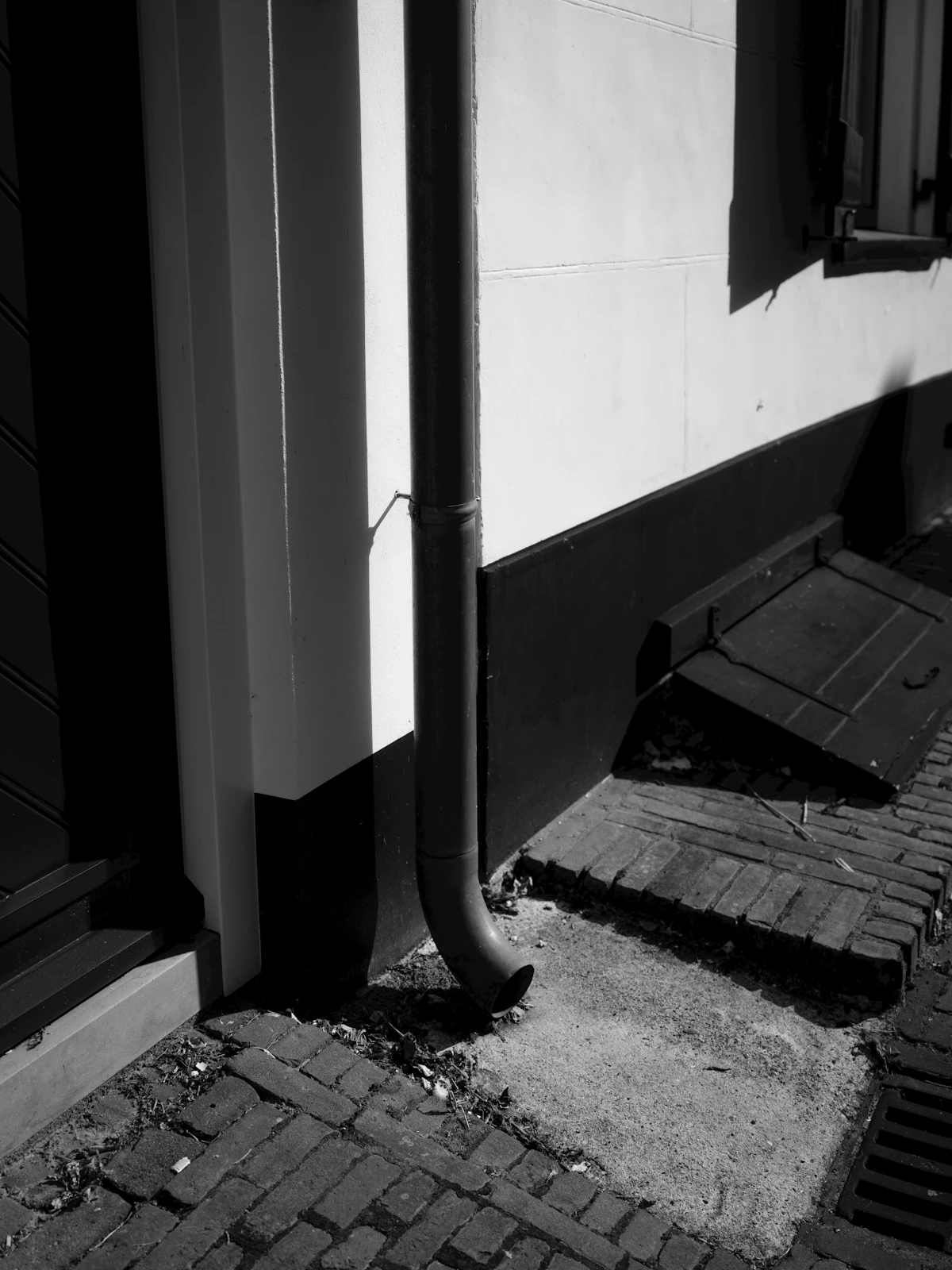 A downspout draining next to a house foundation