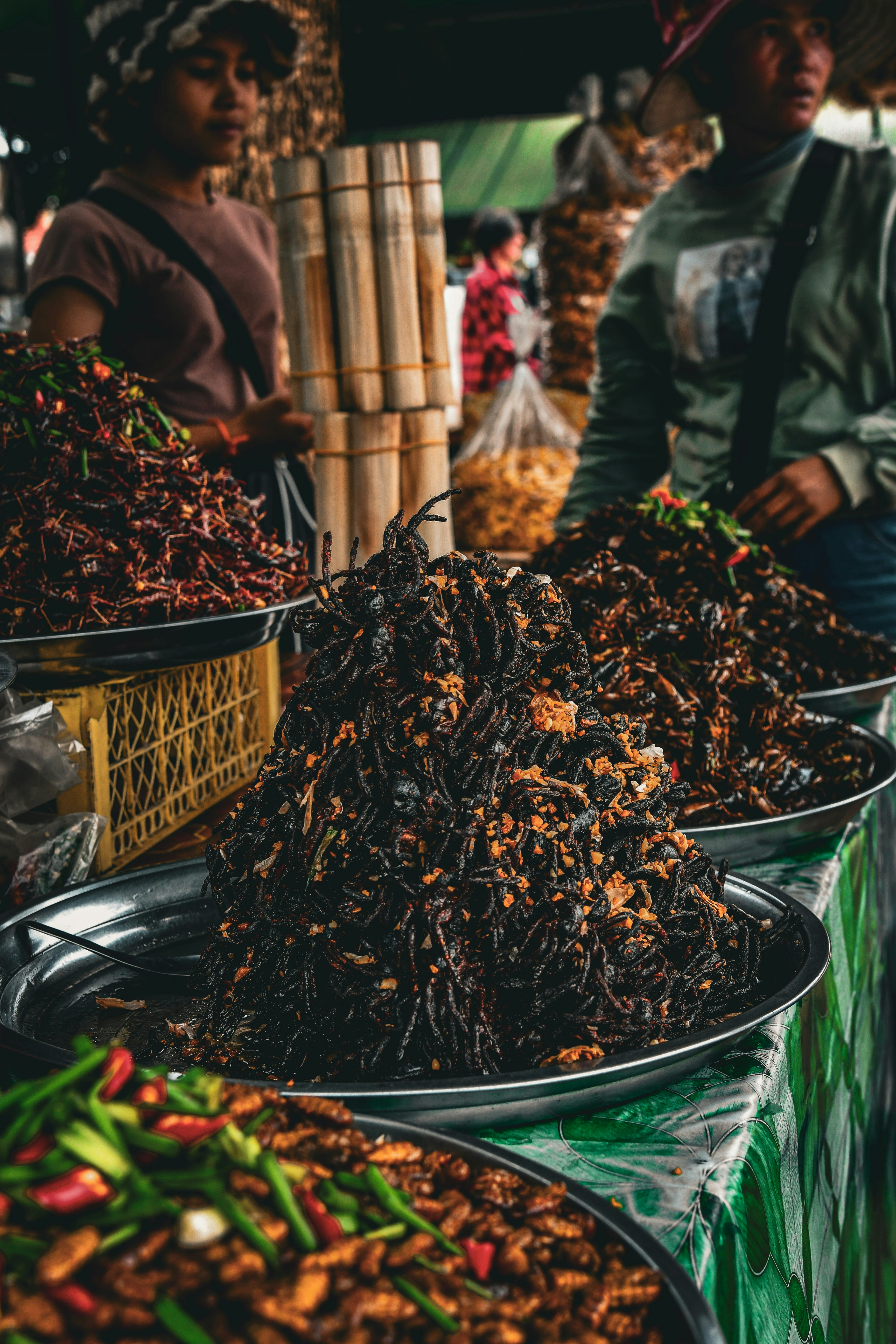 A market stall displays piles of fried insects and chilies.