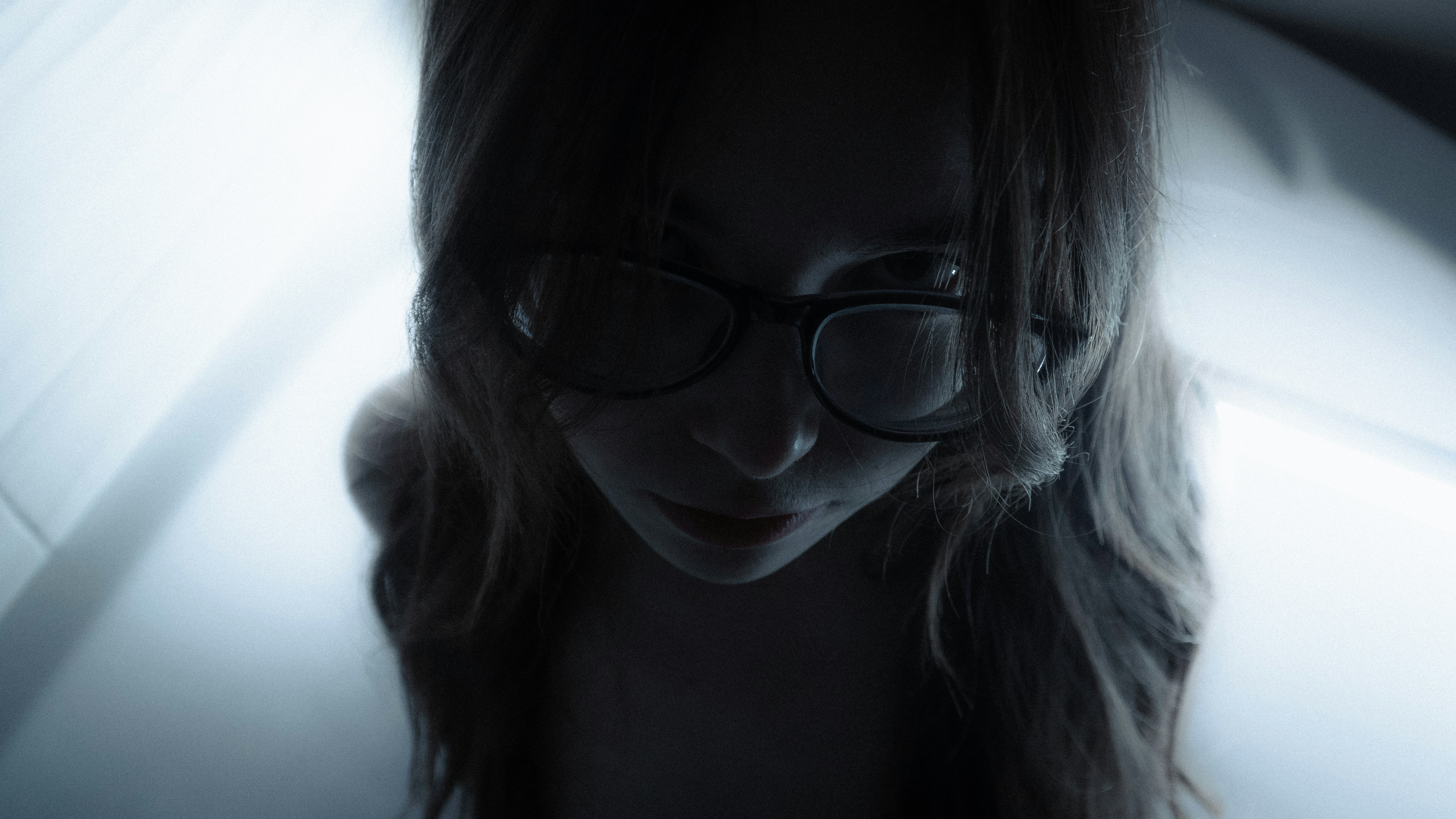 Woman wearing glasses looking down in dim light
