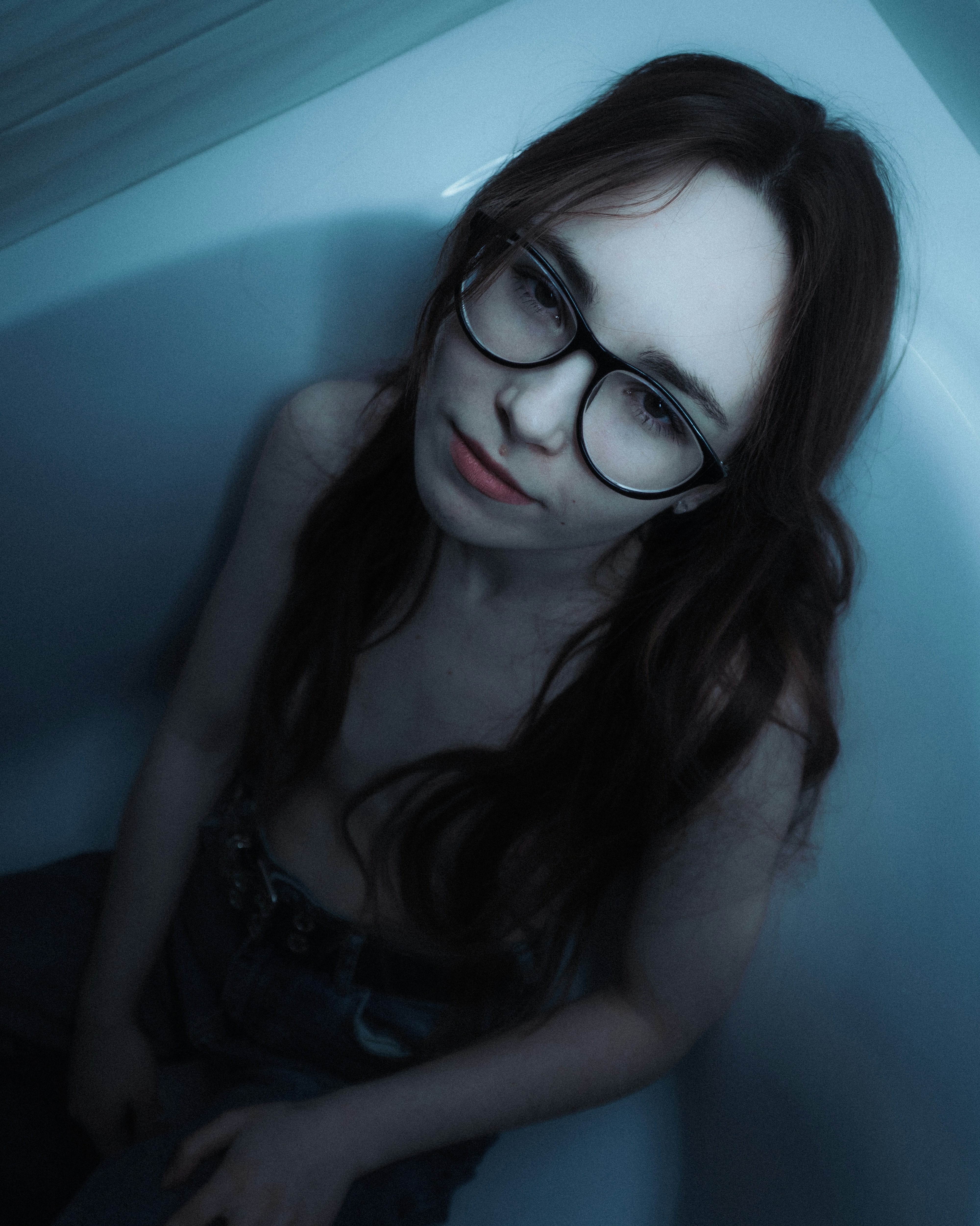 Young woman with glasses in a bathtub