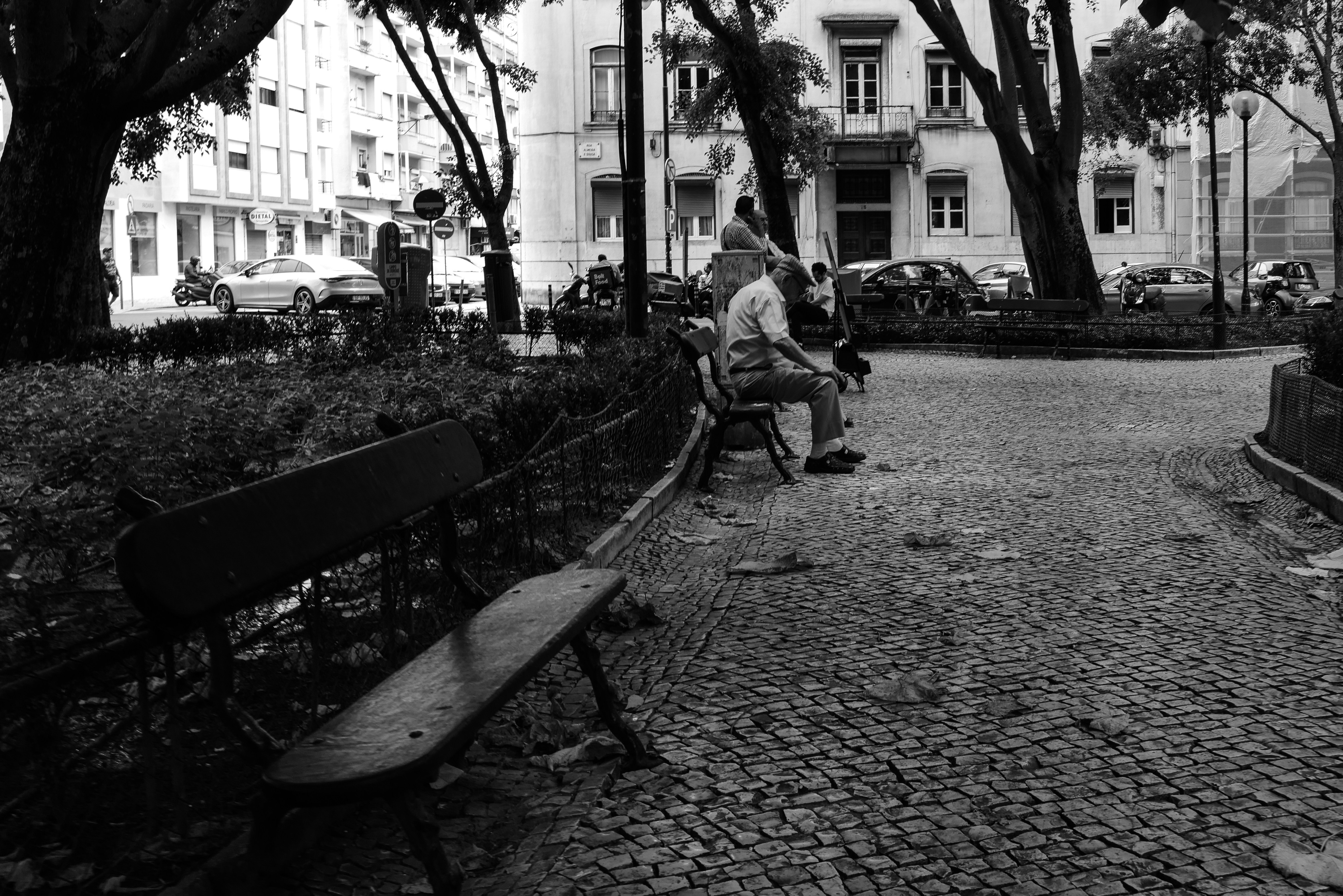 People sitting on benches in a park square.