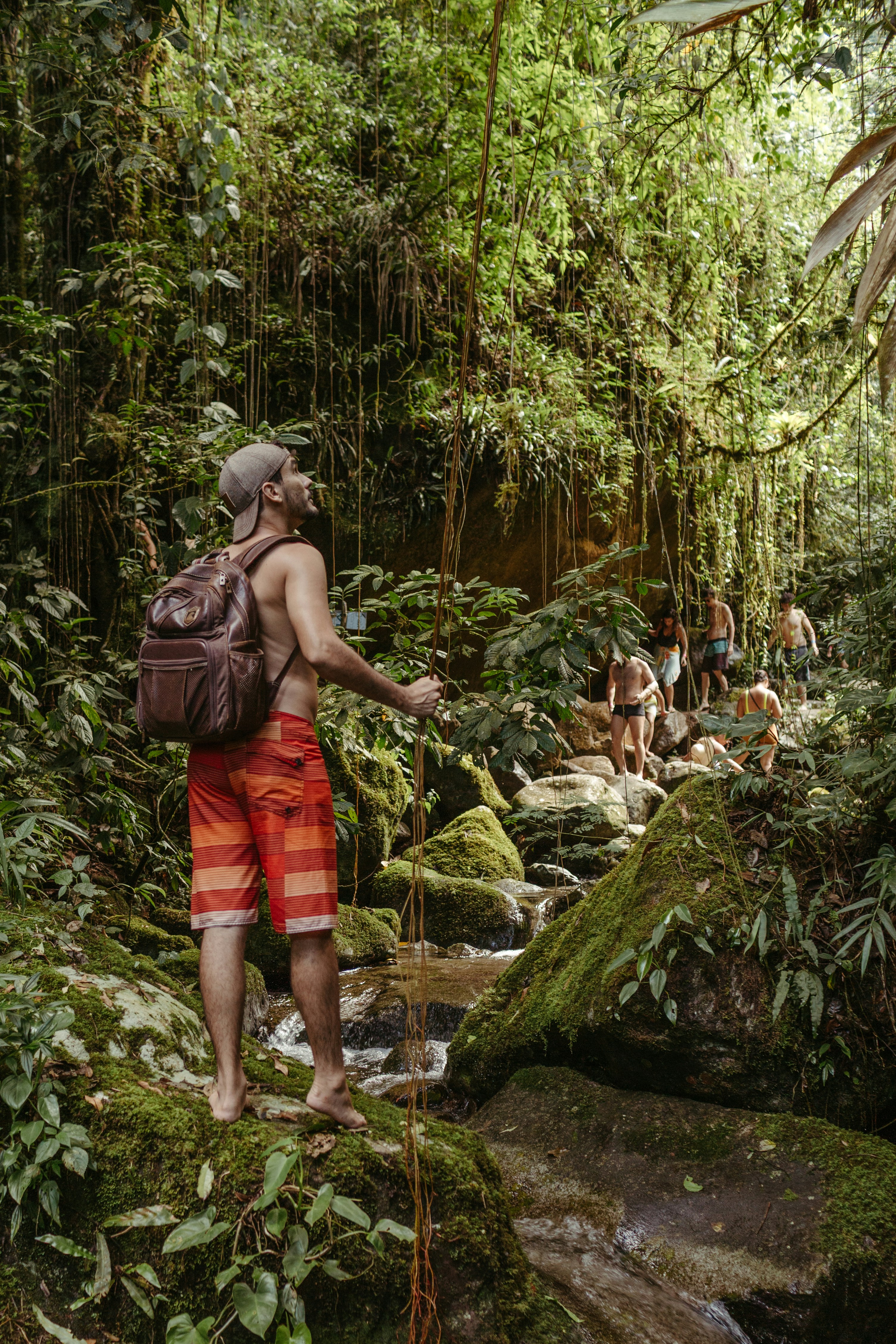 Man with backpack hiking through lush green jungle