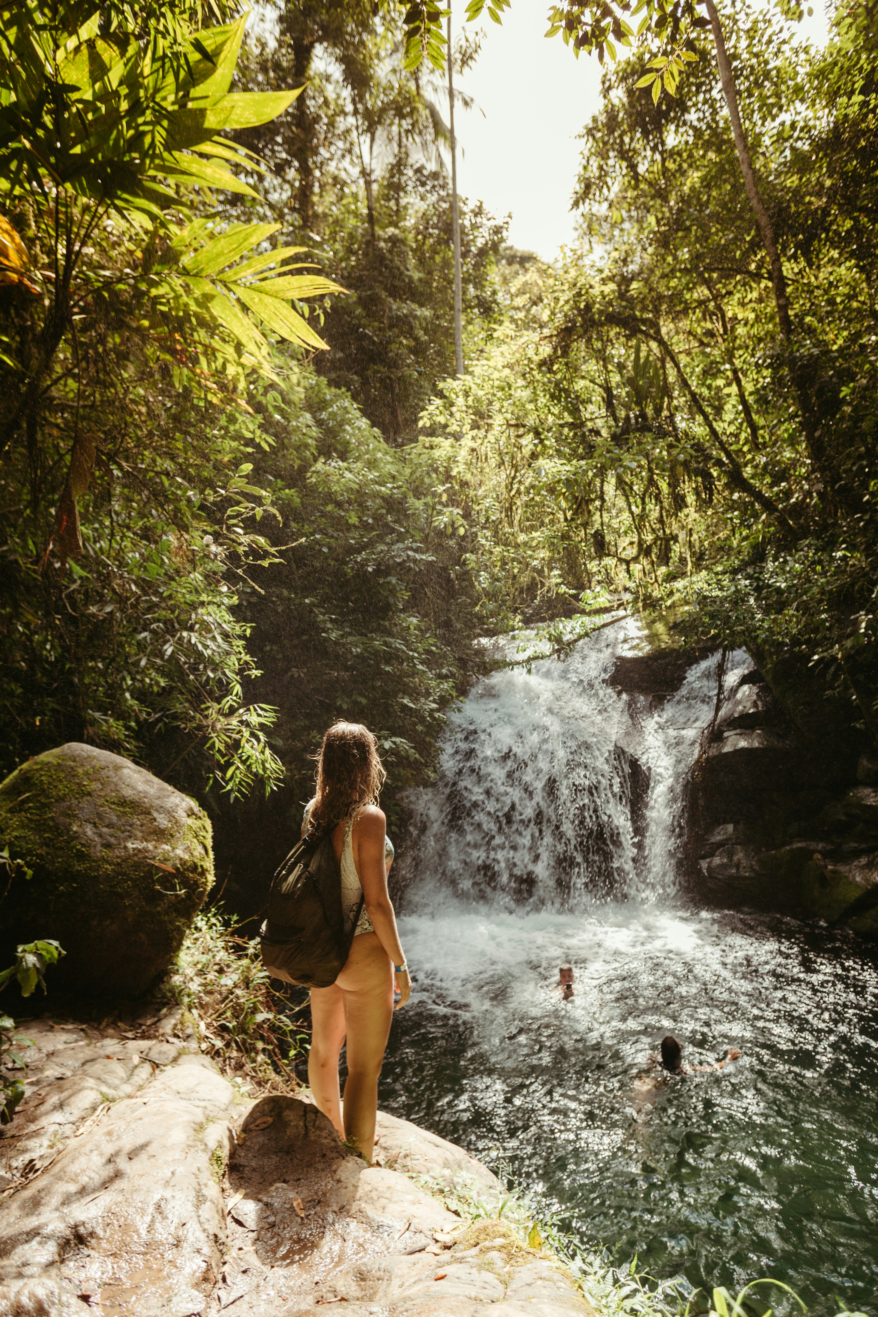 Woman looking at waterfall in lush green jungle