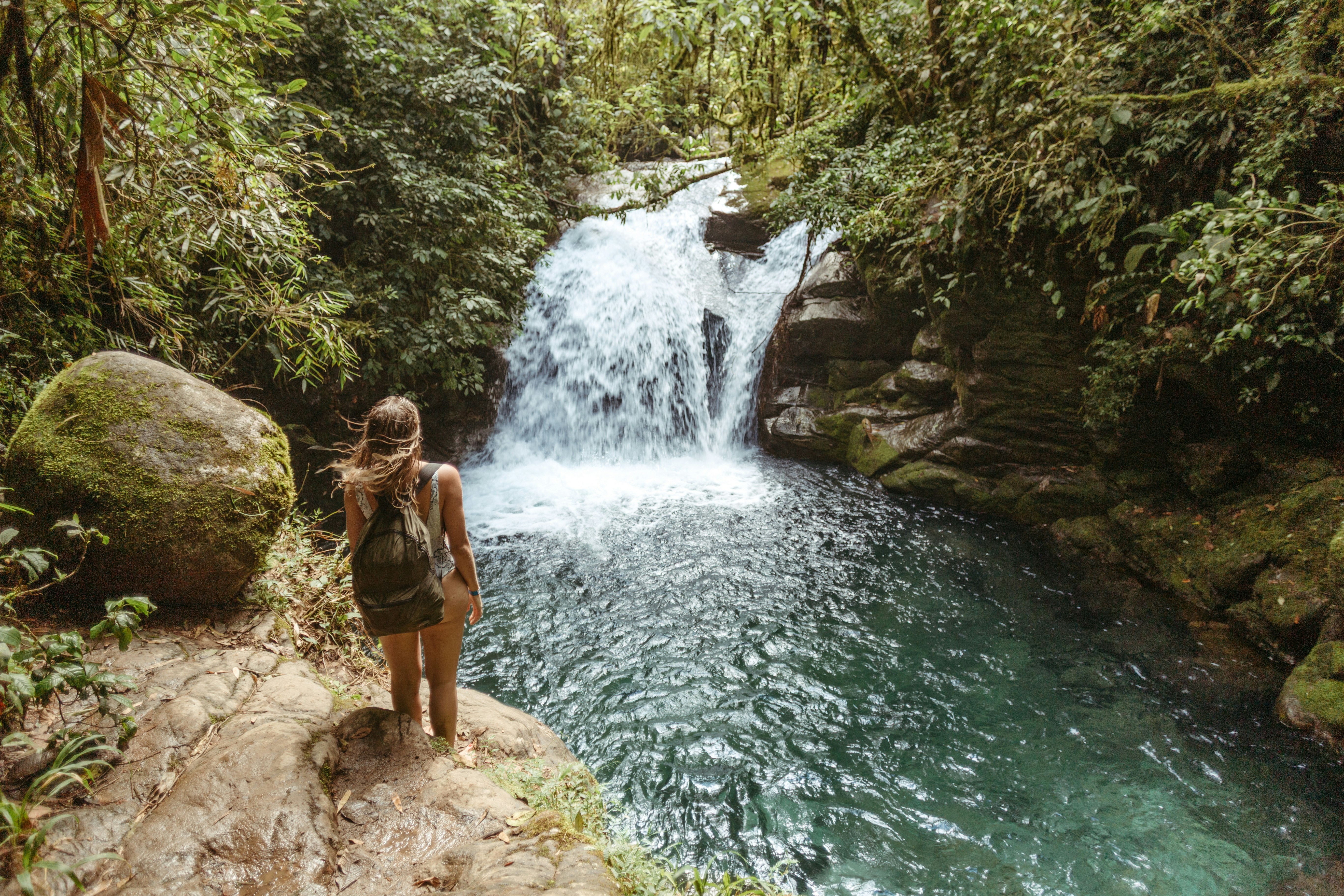 Woman standing by a waterfall in a lush jungle