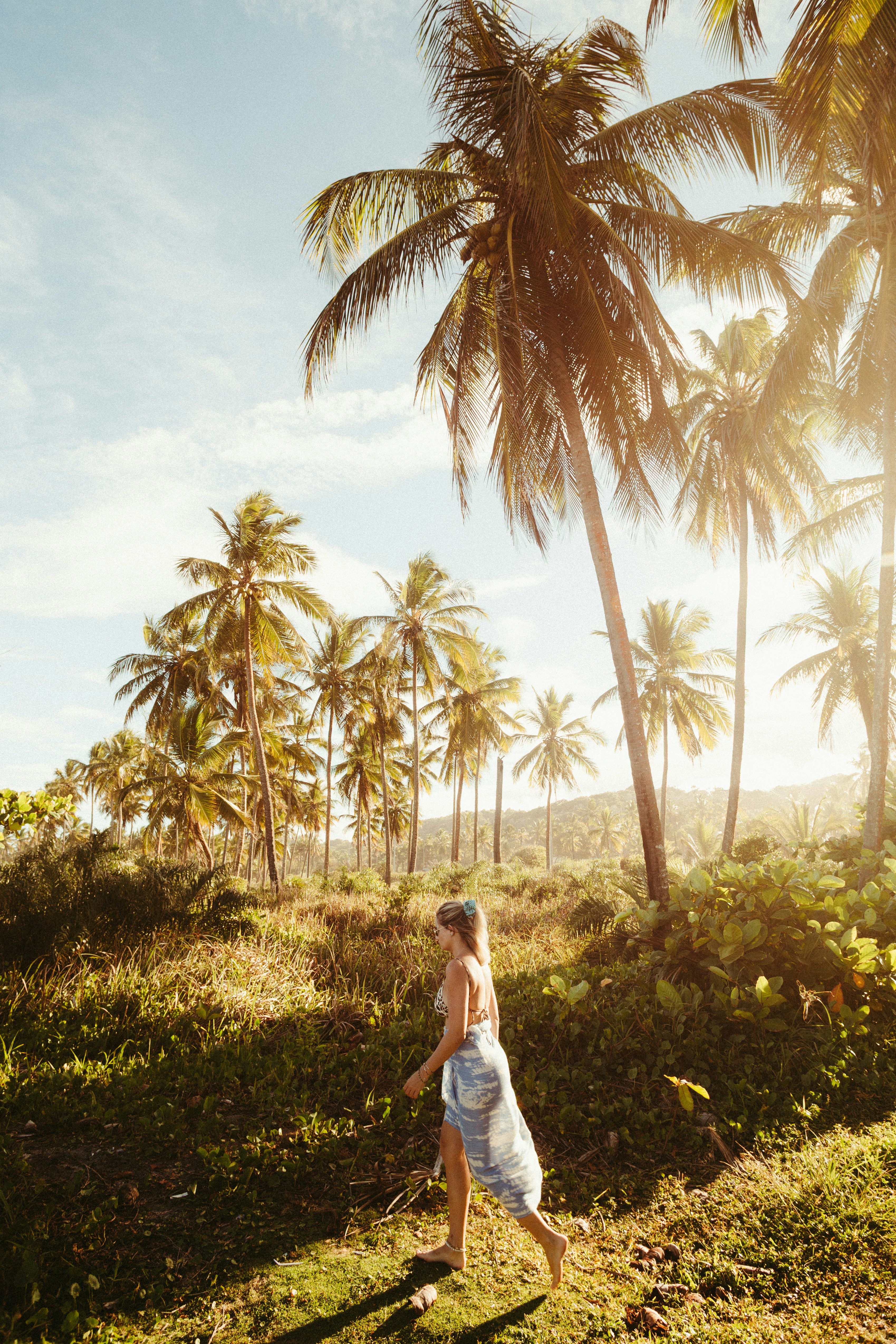 Woman walking through palm trees on a sunny day