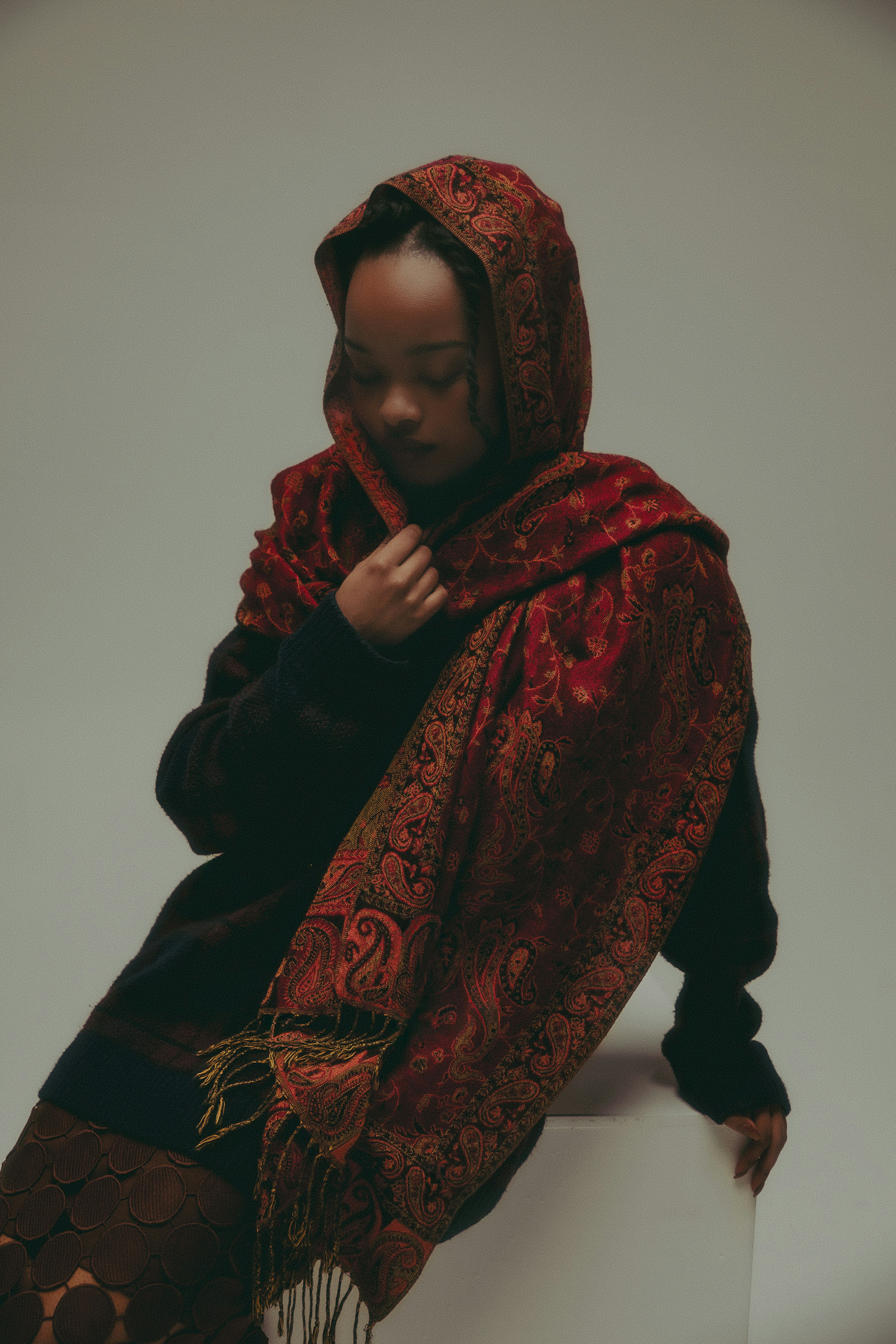 A woman wearing a patterned headscarf and shawl.