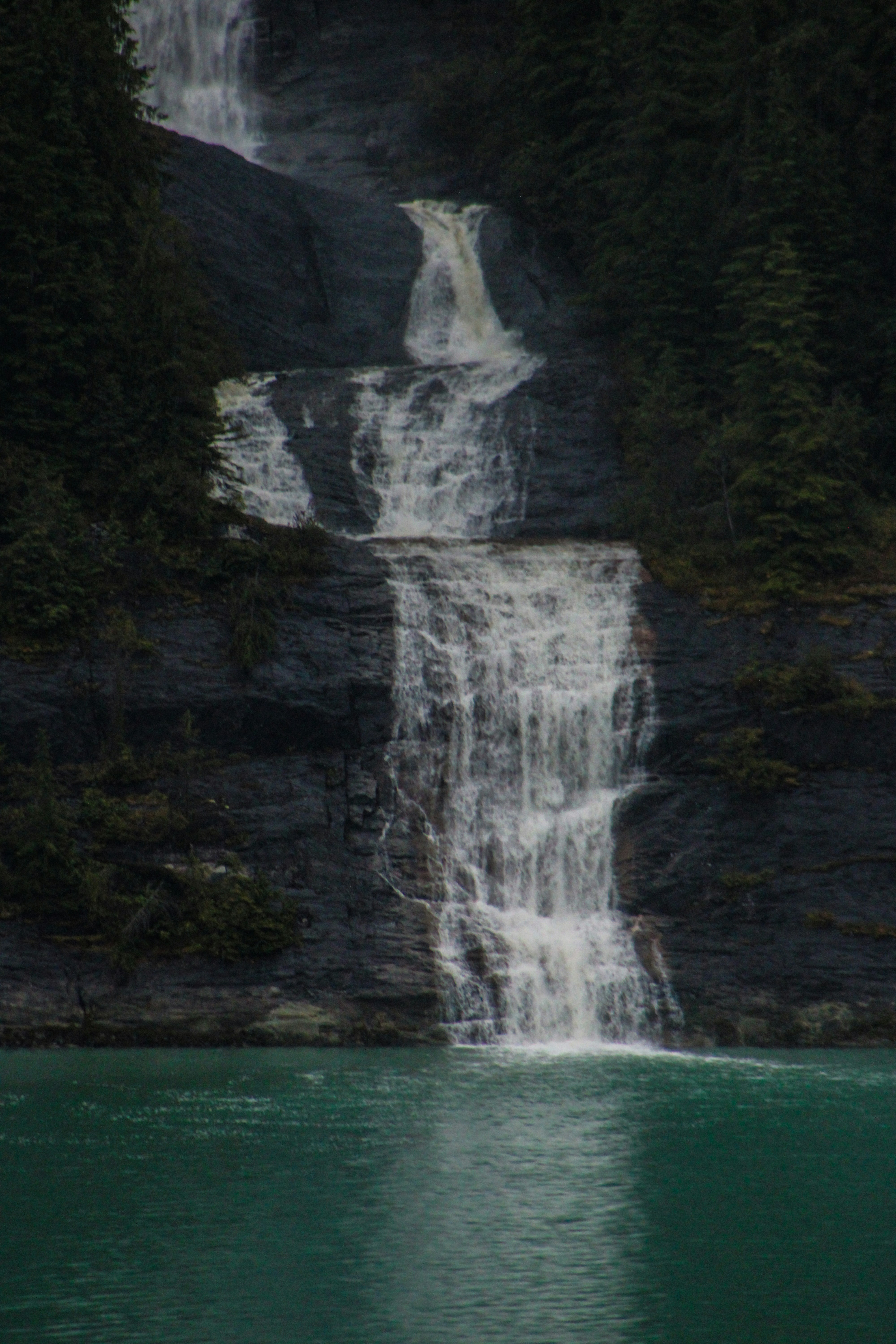 A cascading waterfall flows into a turquoise body of water.