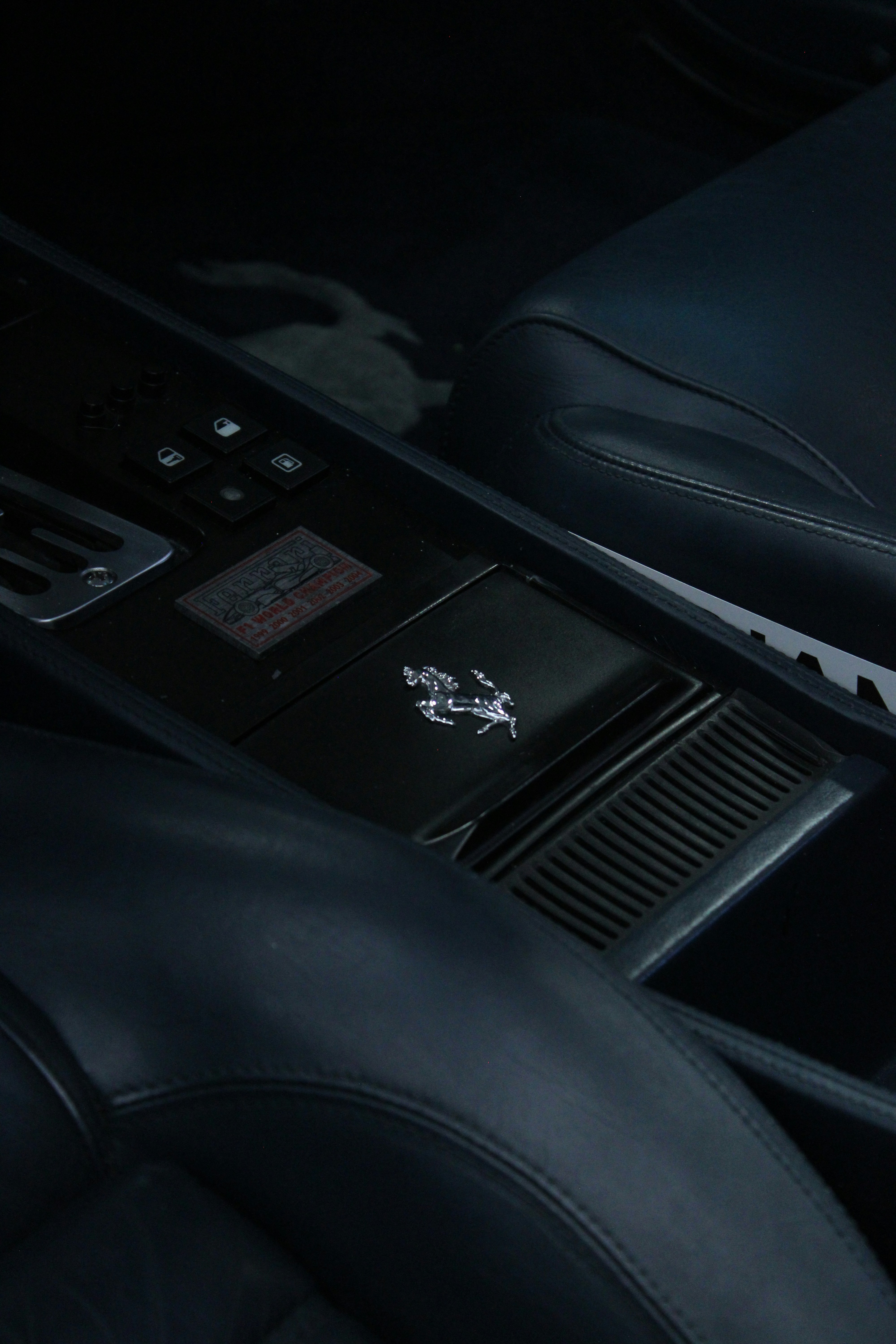 Close-up of a black leather car interior with ferrari logo.