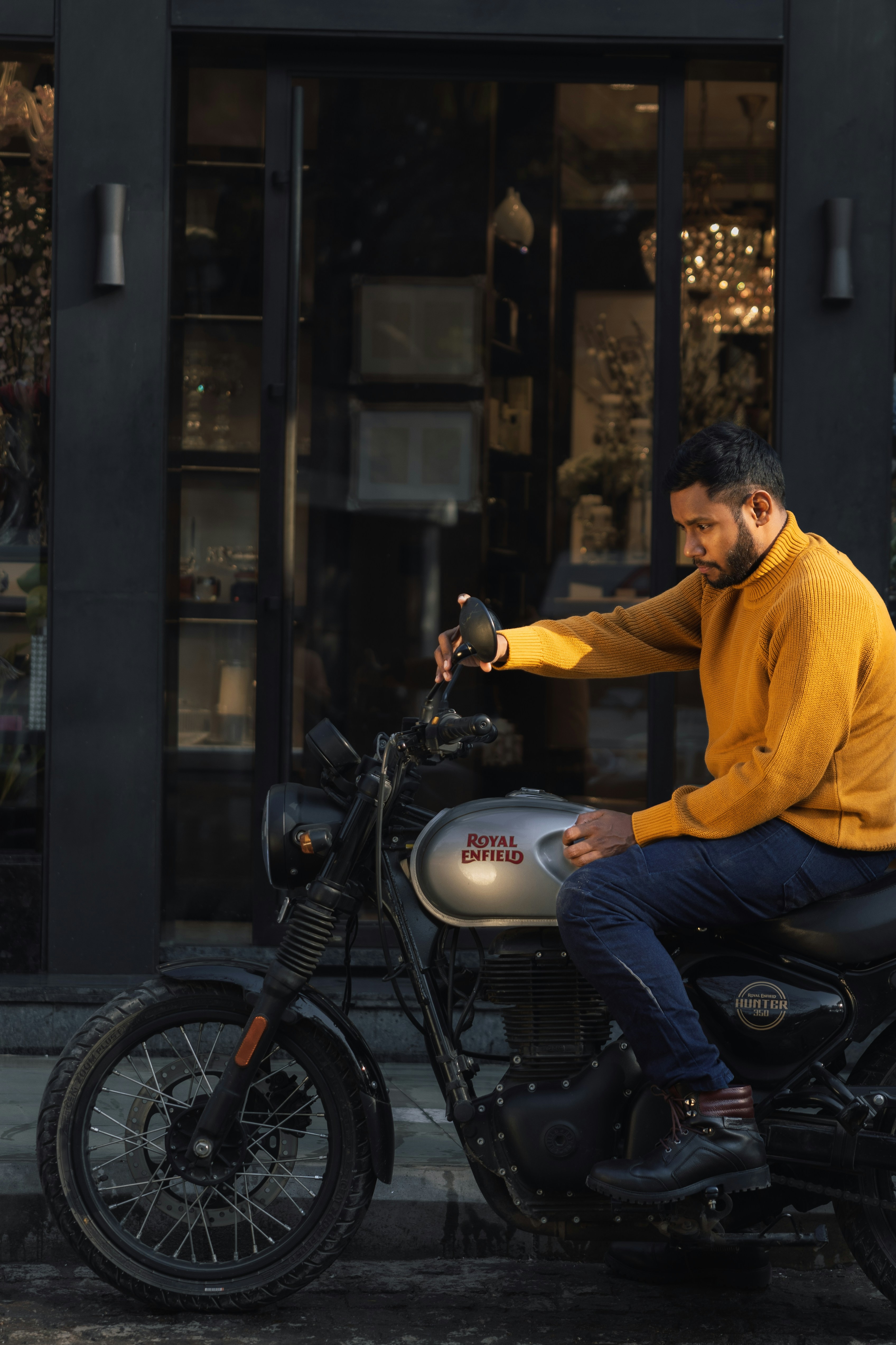 Man in yellow sweater sitting on a motorcycle.