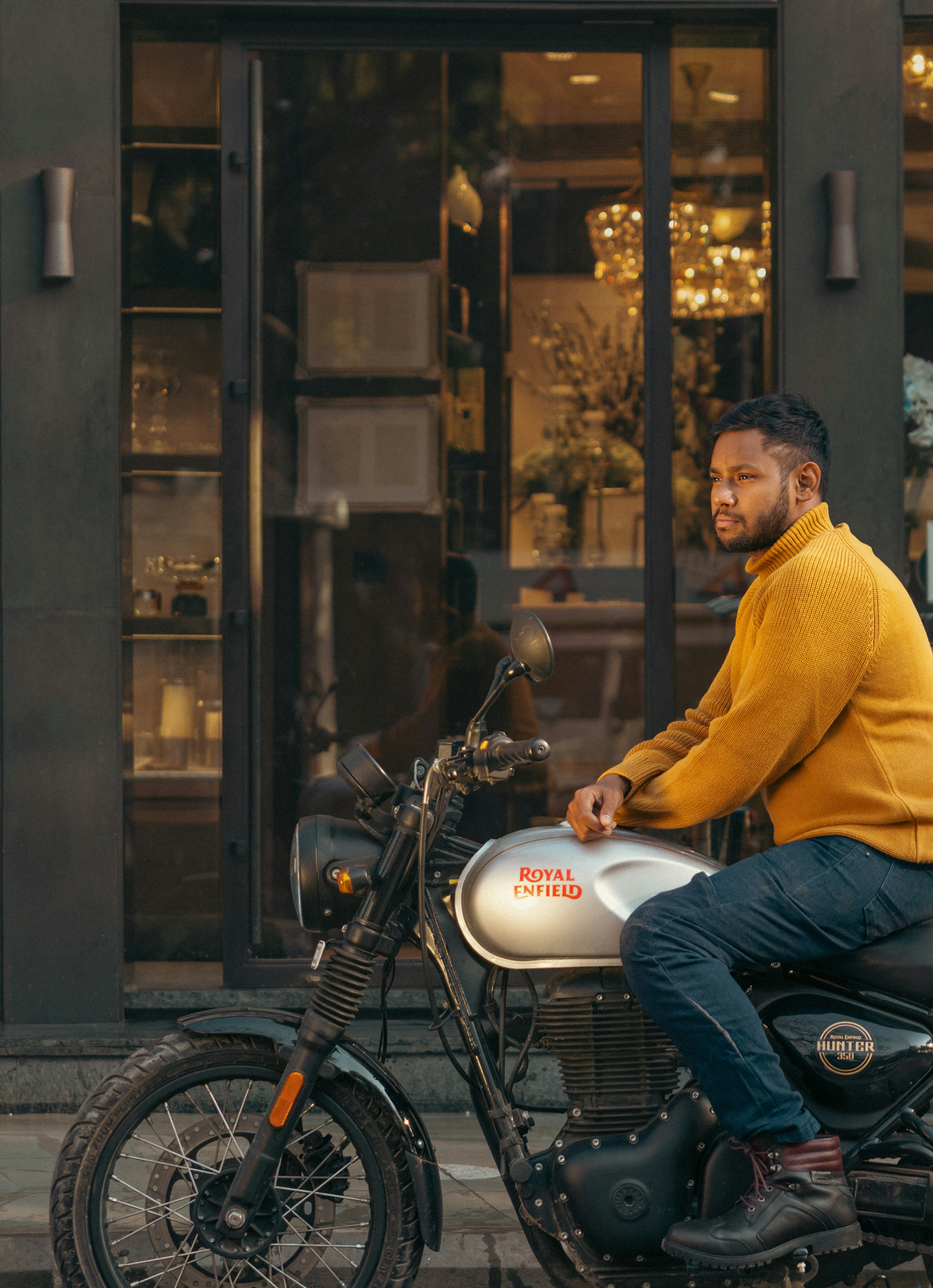 Man wearing yellow sweater riding a motorcycle.