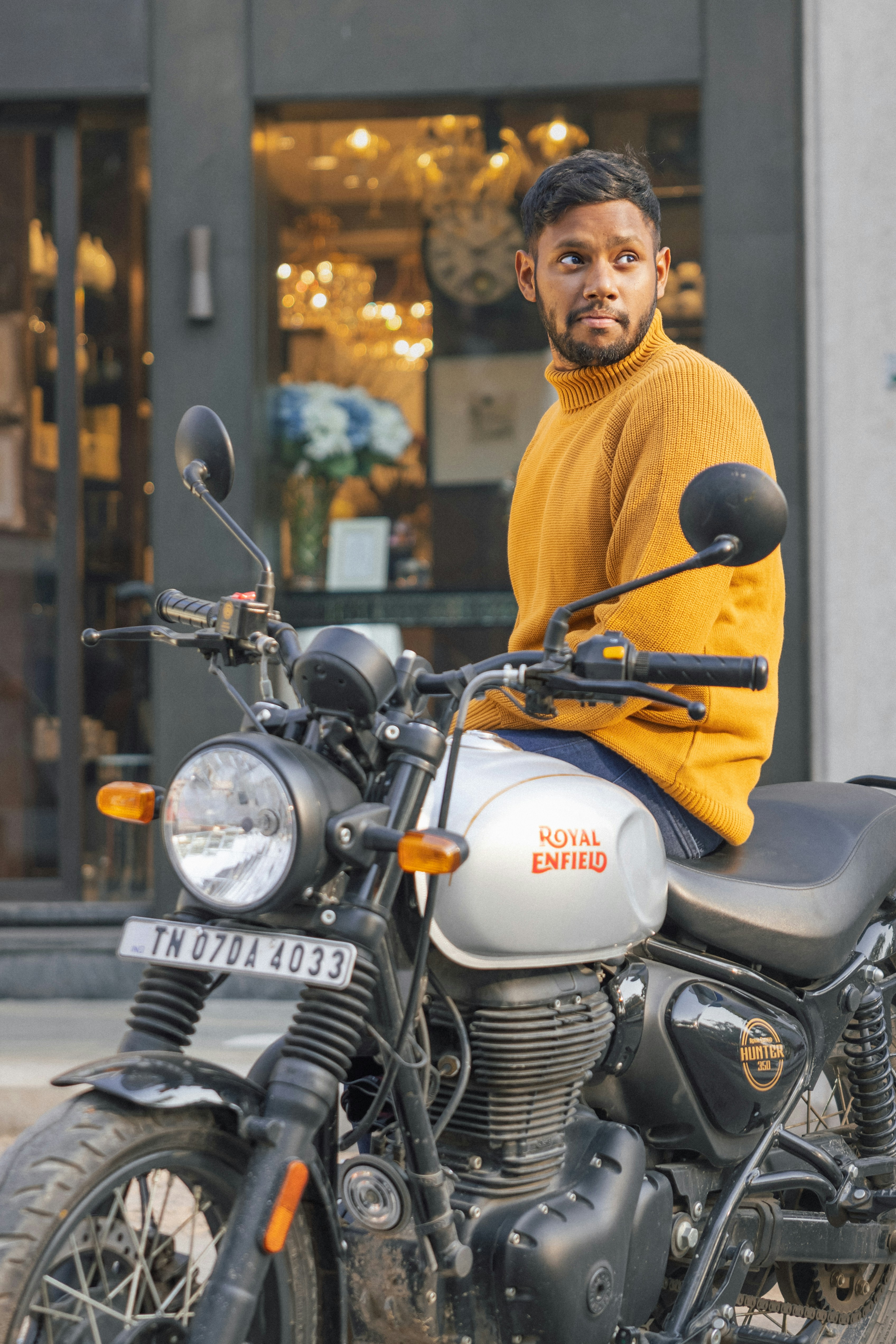 Man in yellow sweater sitting on a motorcycle.