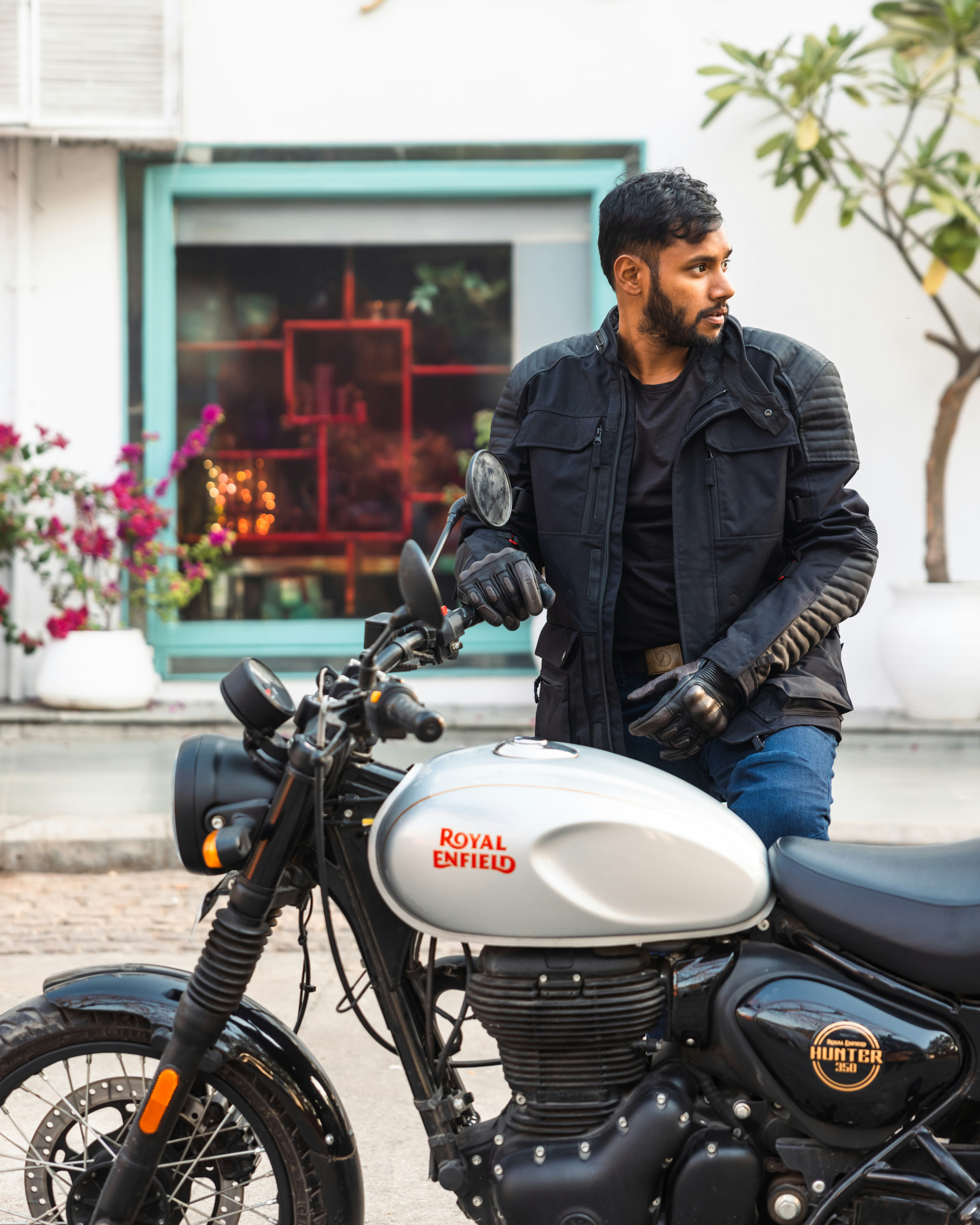 Man in jacket leaning on a silver motorcycle