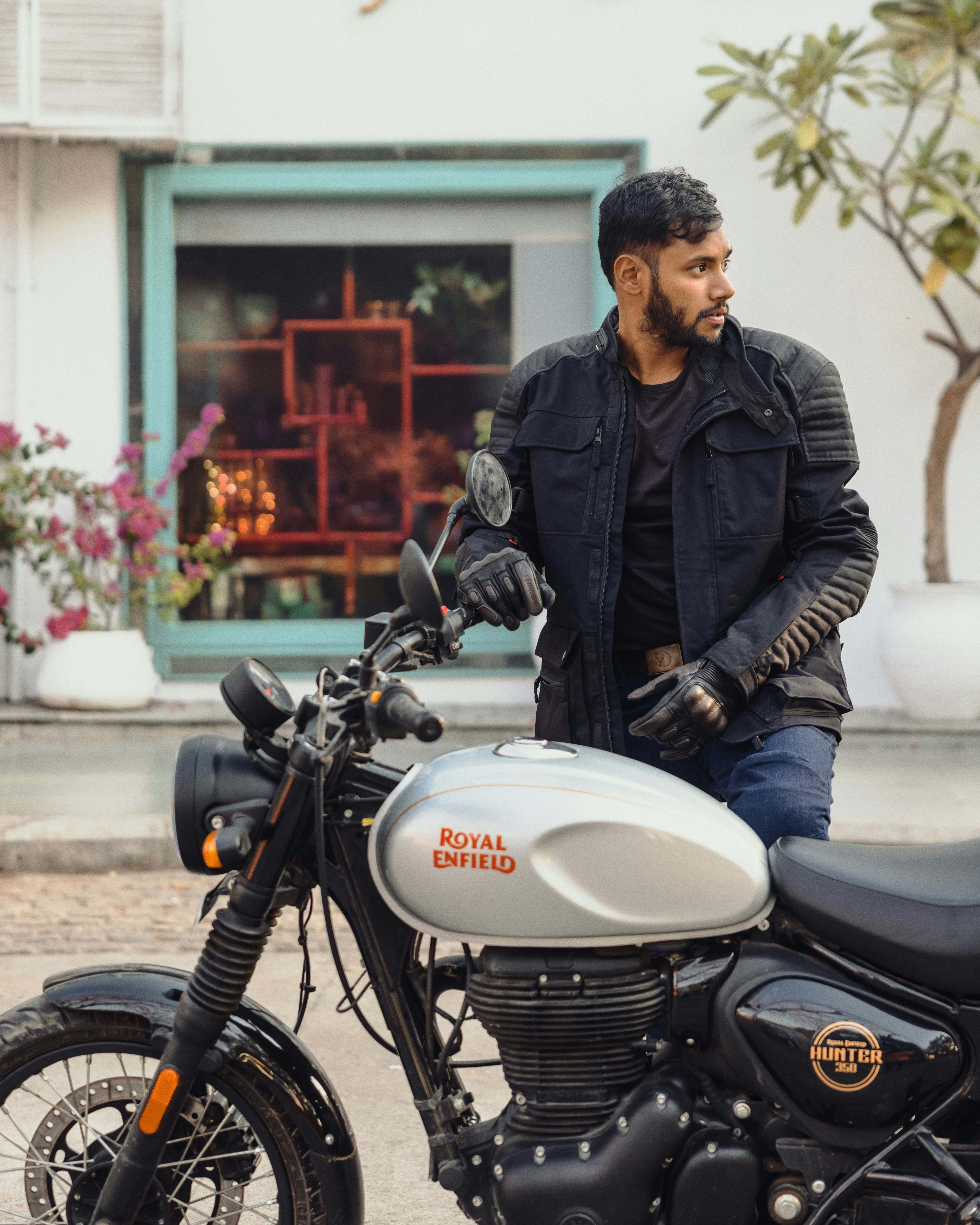 Man in jacket leaning on silver motorcycle