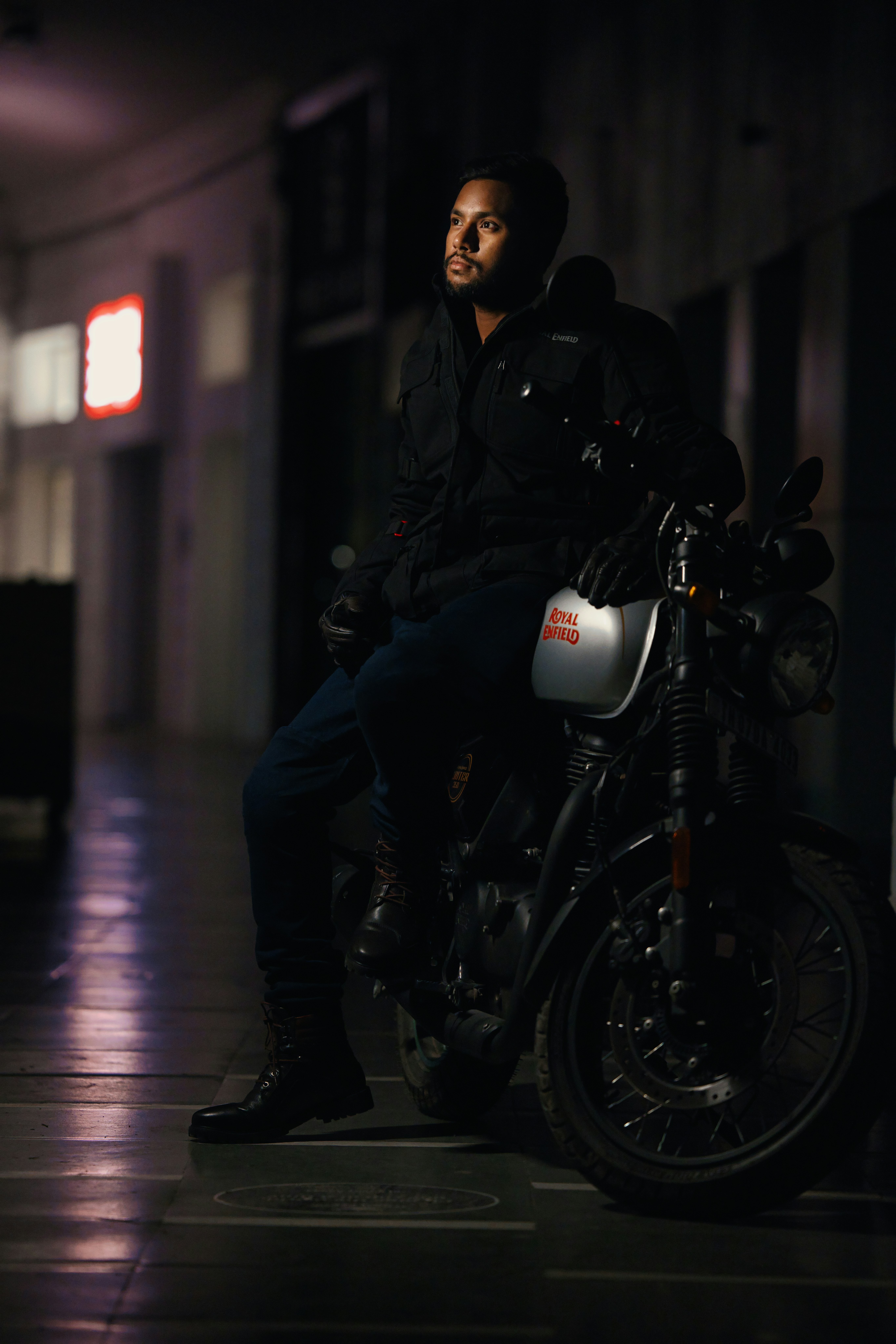 Man in black jacket sits on motorcycle at night.
