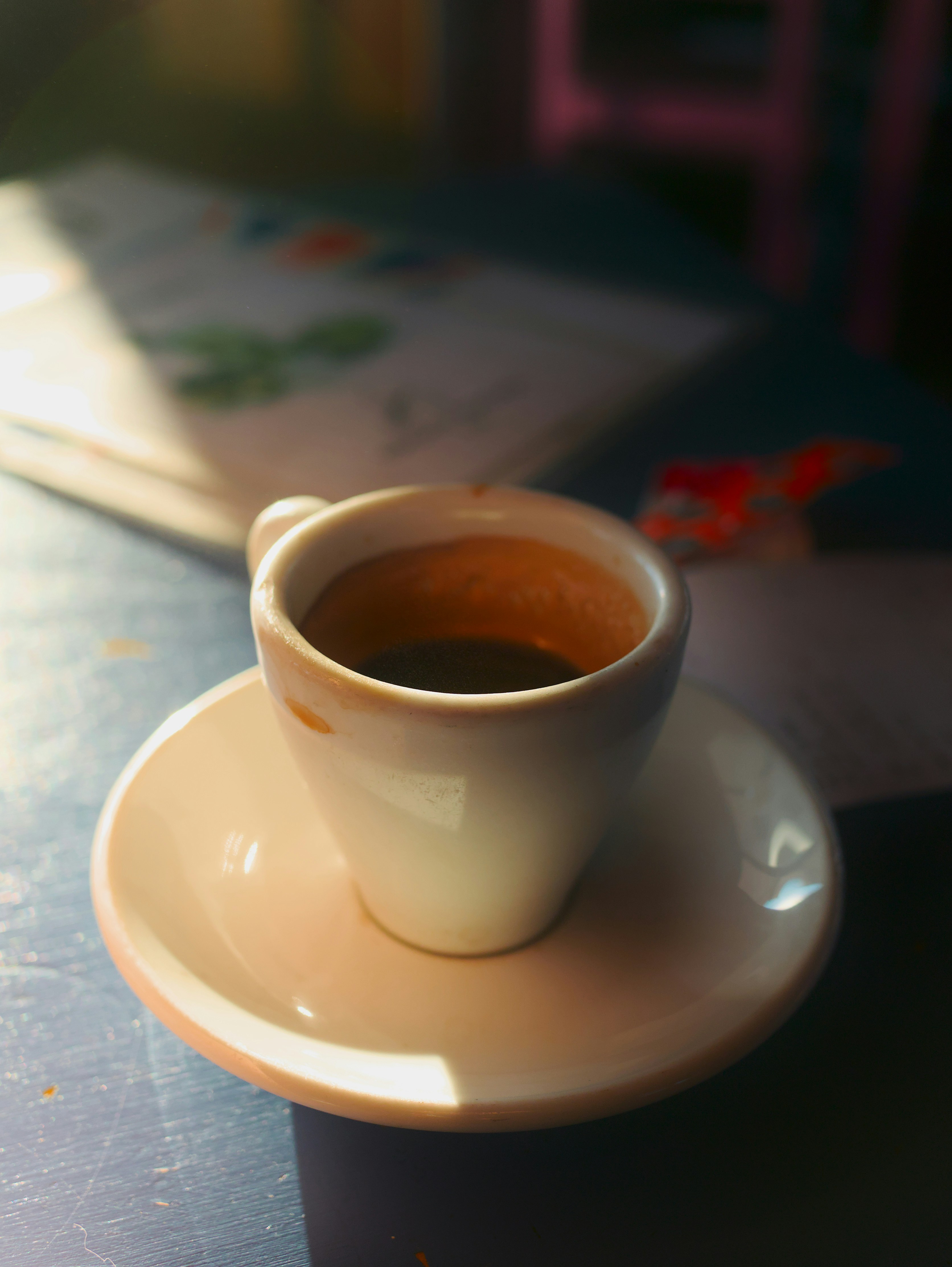 A small cup of black coffee on a saucer.