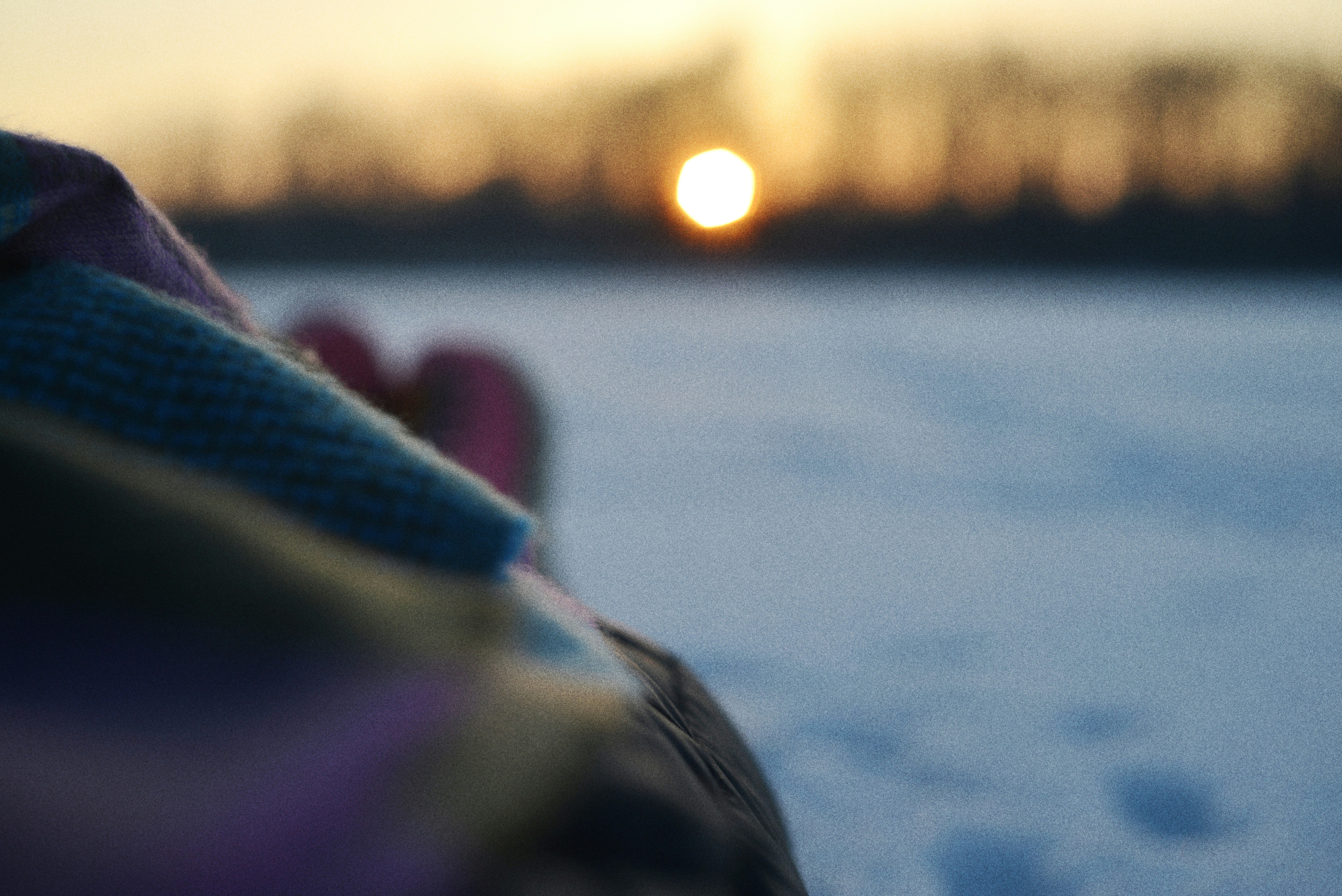 눈 덮인 풍경 위로 흐릿한 석양이 다채로운 옷과 함께 보였다