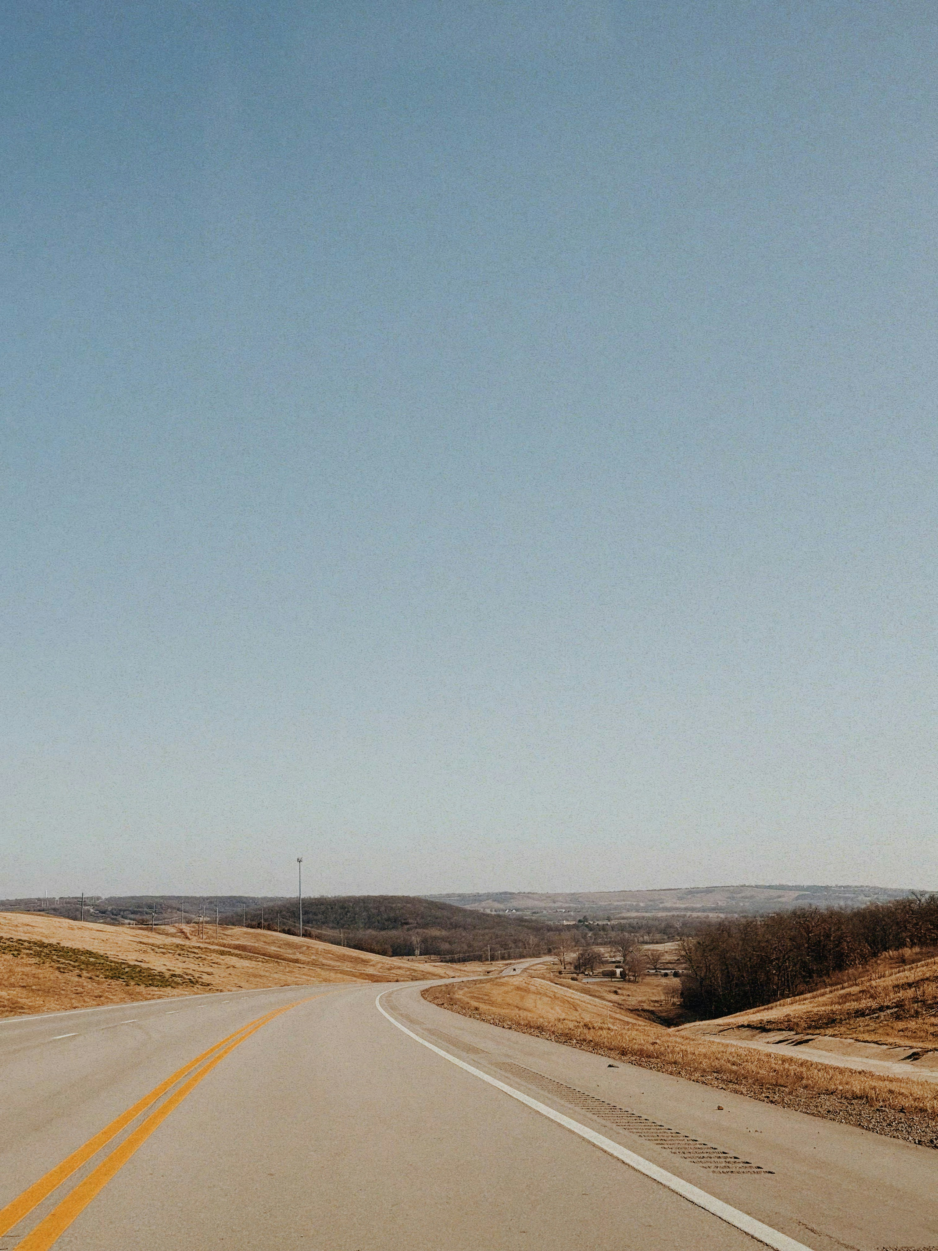 Una strada tortuosa tra dolci colline sotto un cielo limpido