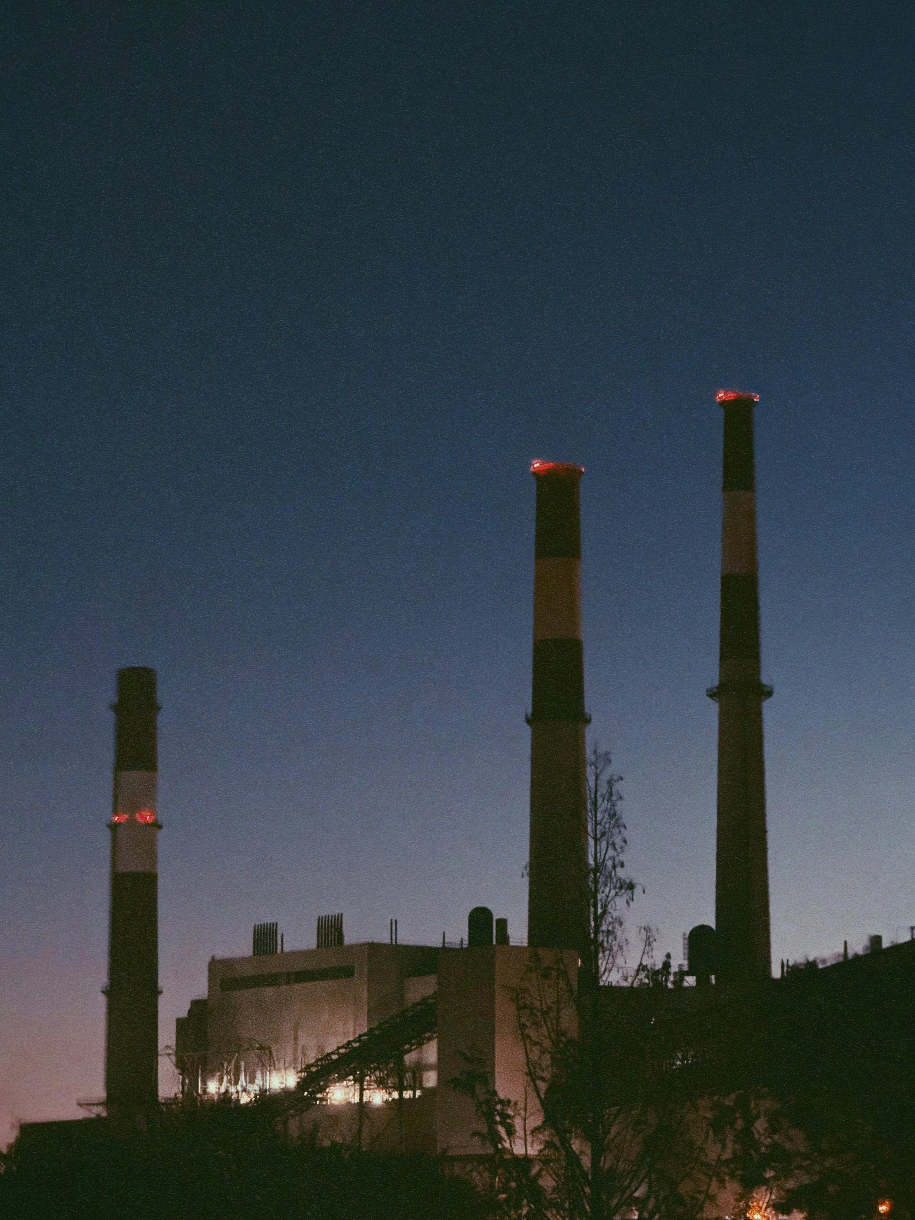 Camini industriali al crepuscolo con coperchi luminosi