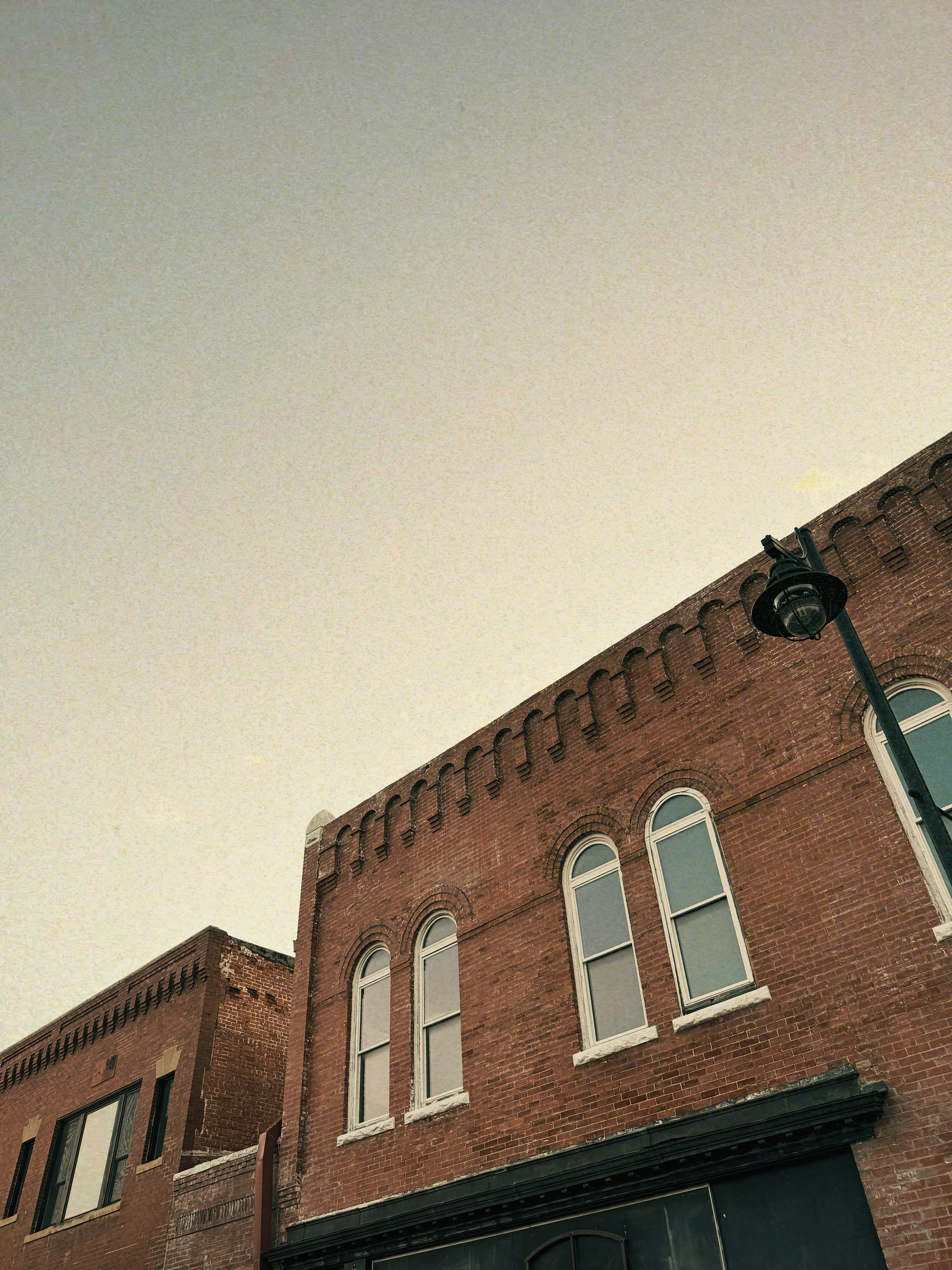 Edifici in mattoni con finestre ad arco e un lampione.