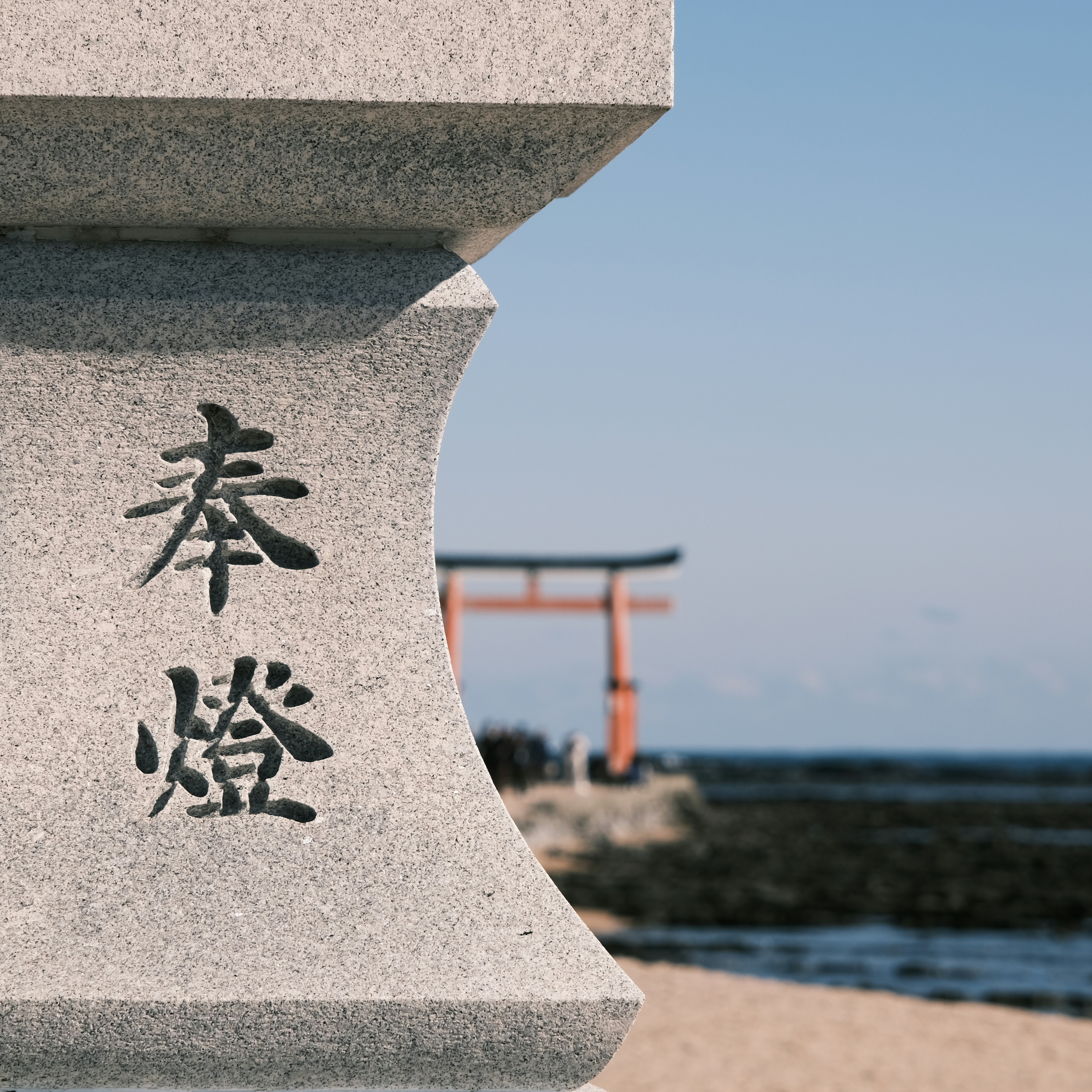 Stone lantern with japanese characters and torii gate.