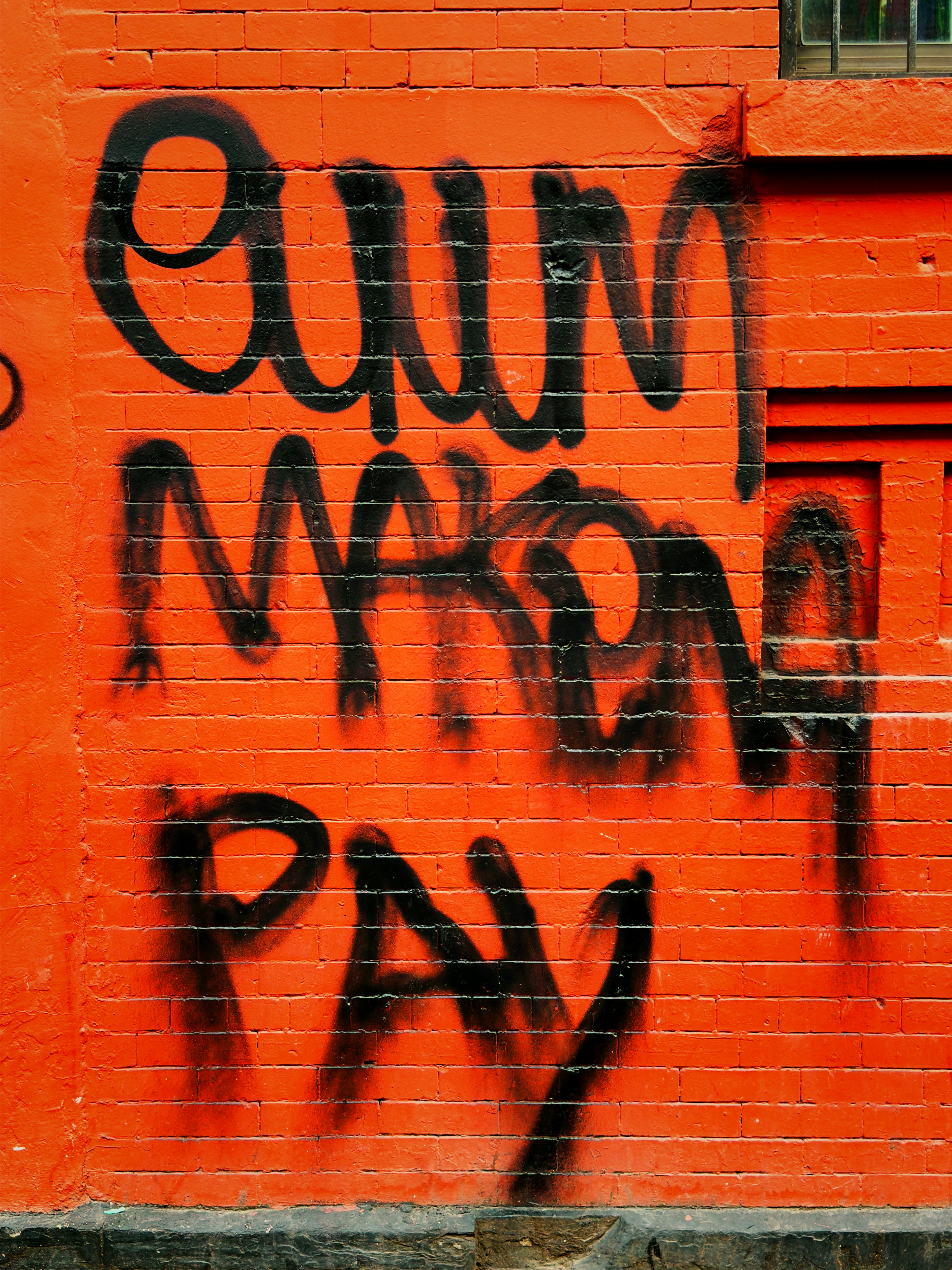 주황색 벽돌 벽에 검은 그래피티.