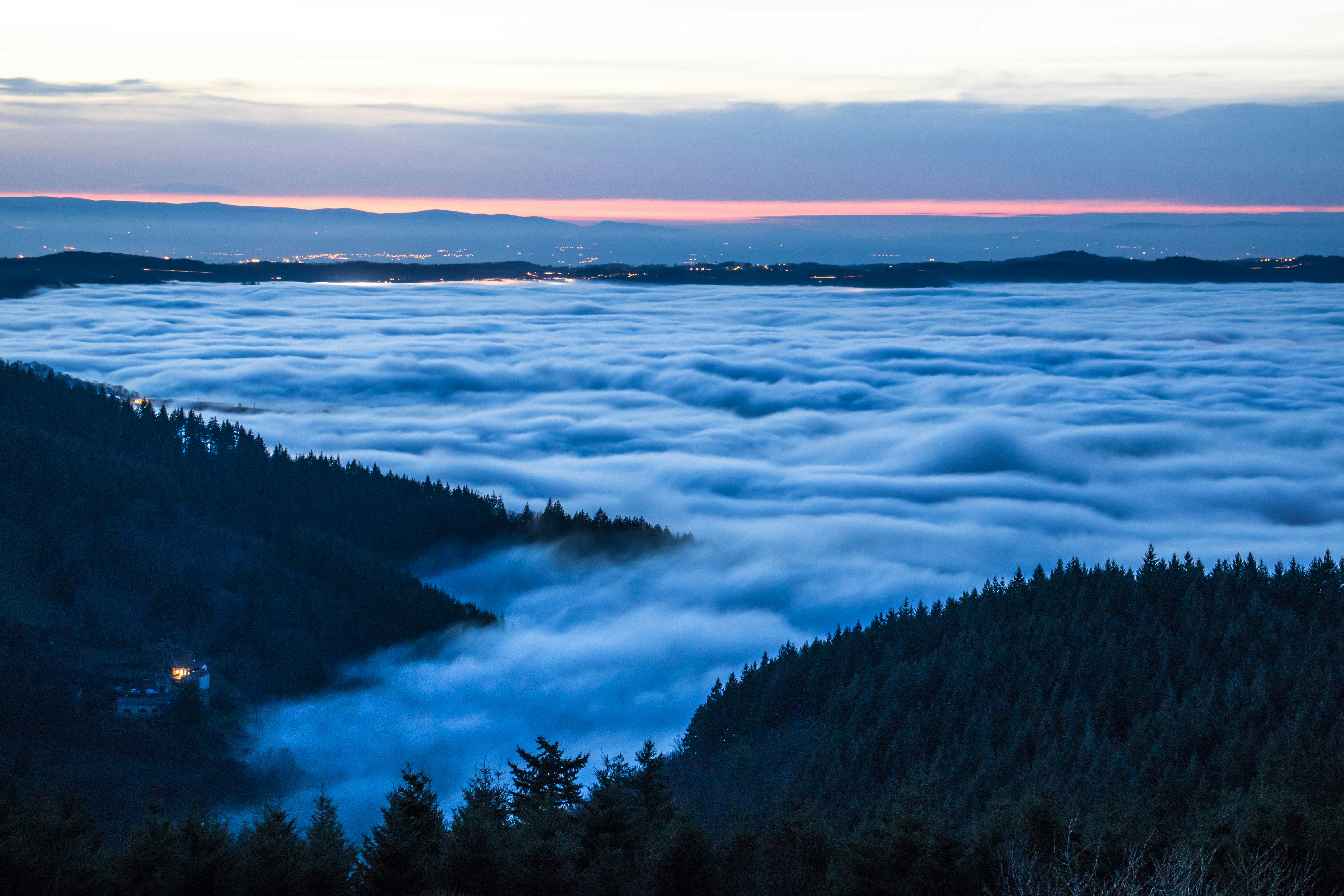 Sea of clouds over forest valley at dusk