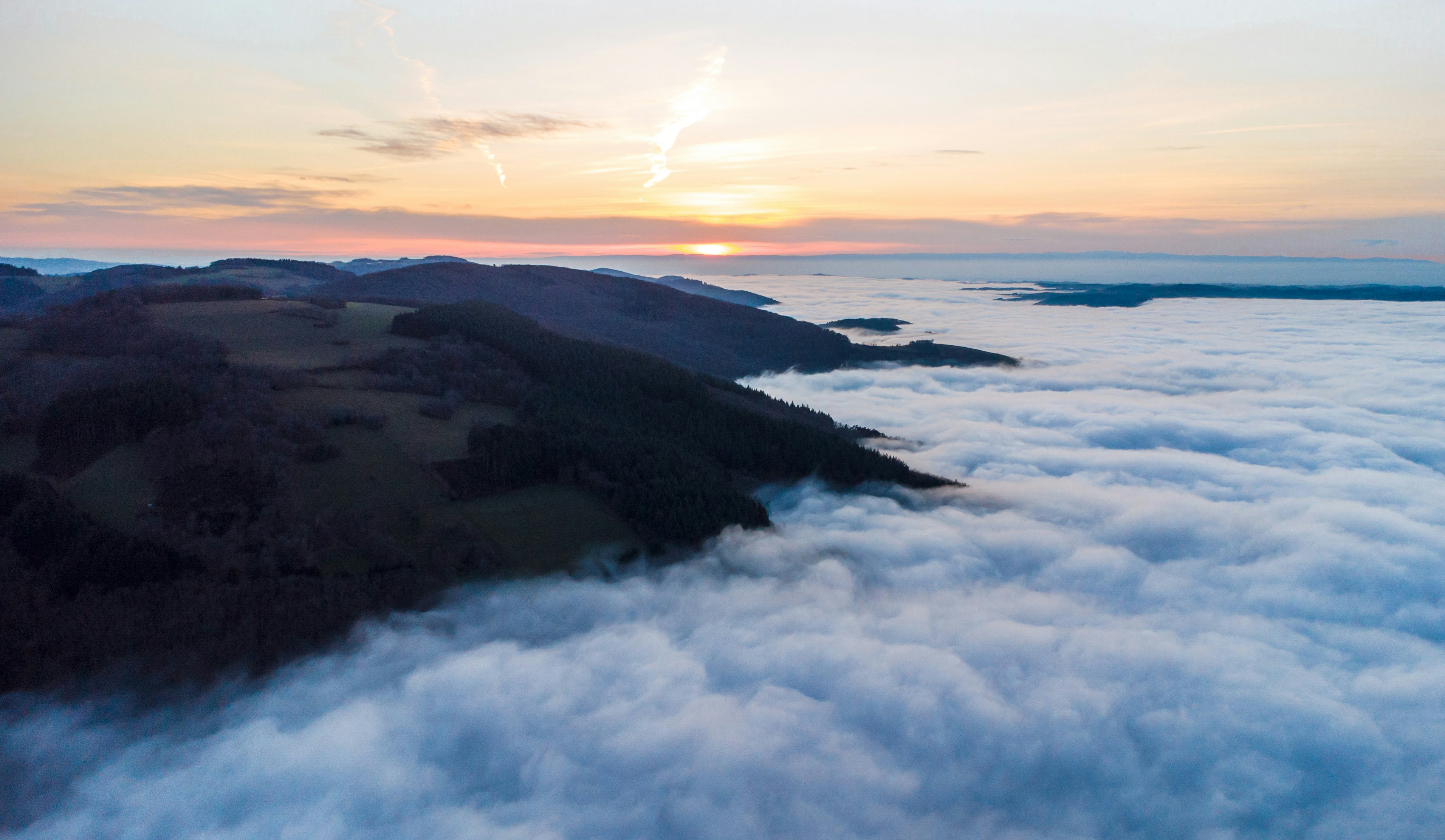 Sunrise over a sea of clouds above hills