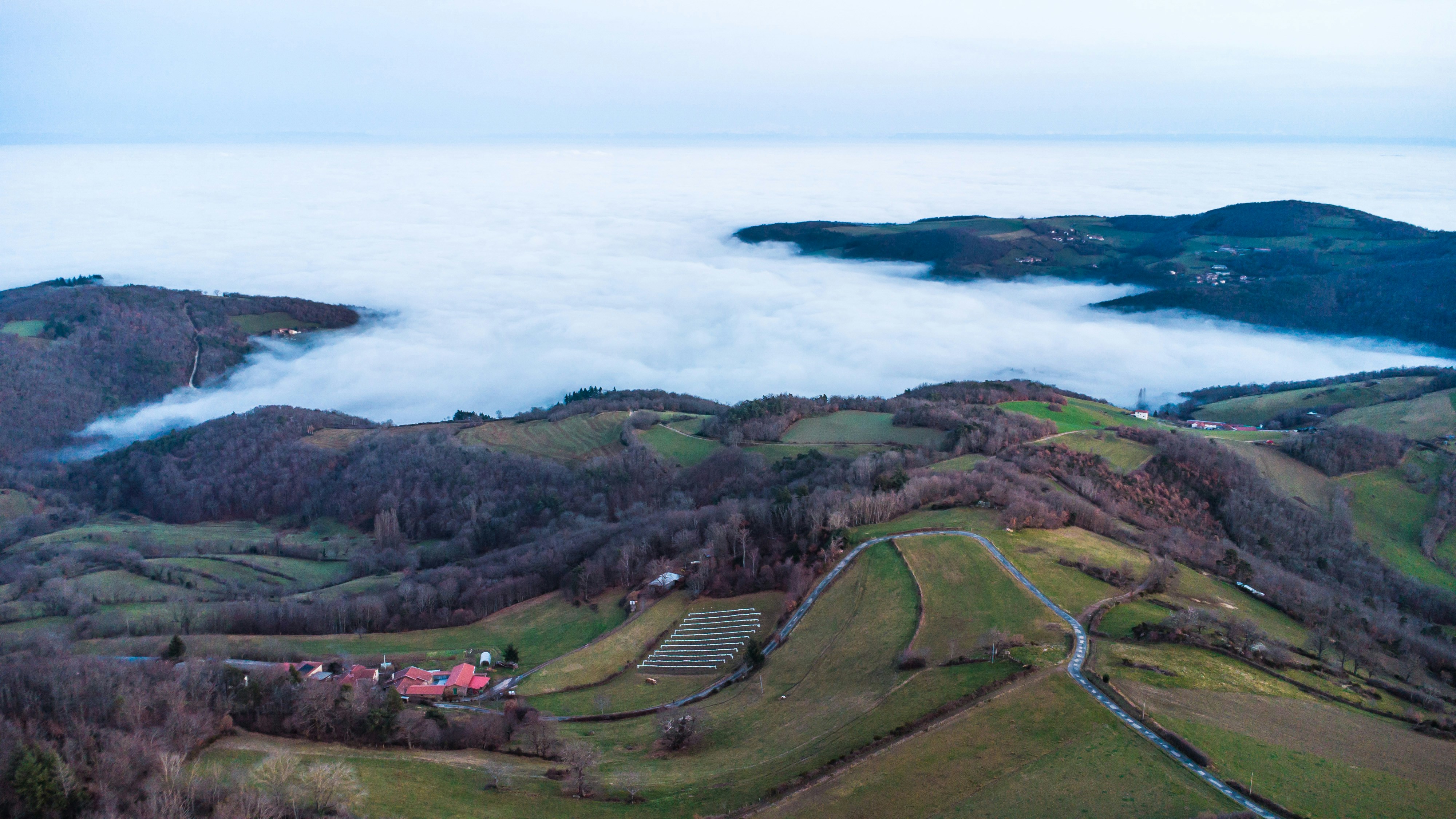 Rolling hills covered in fog with a small village below.
