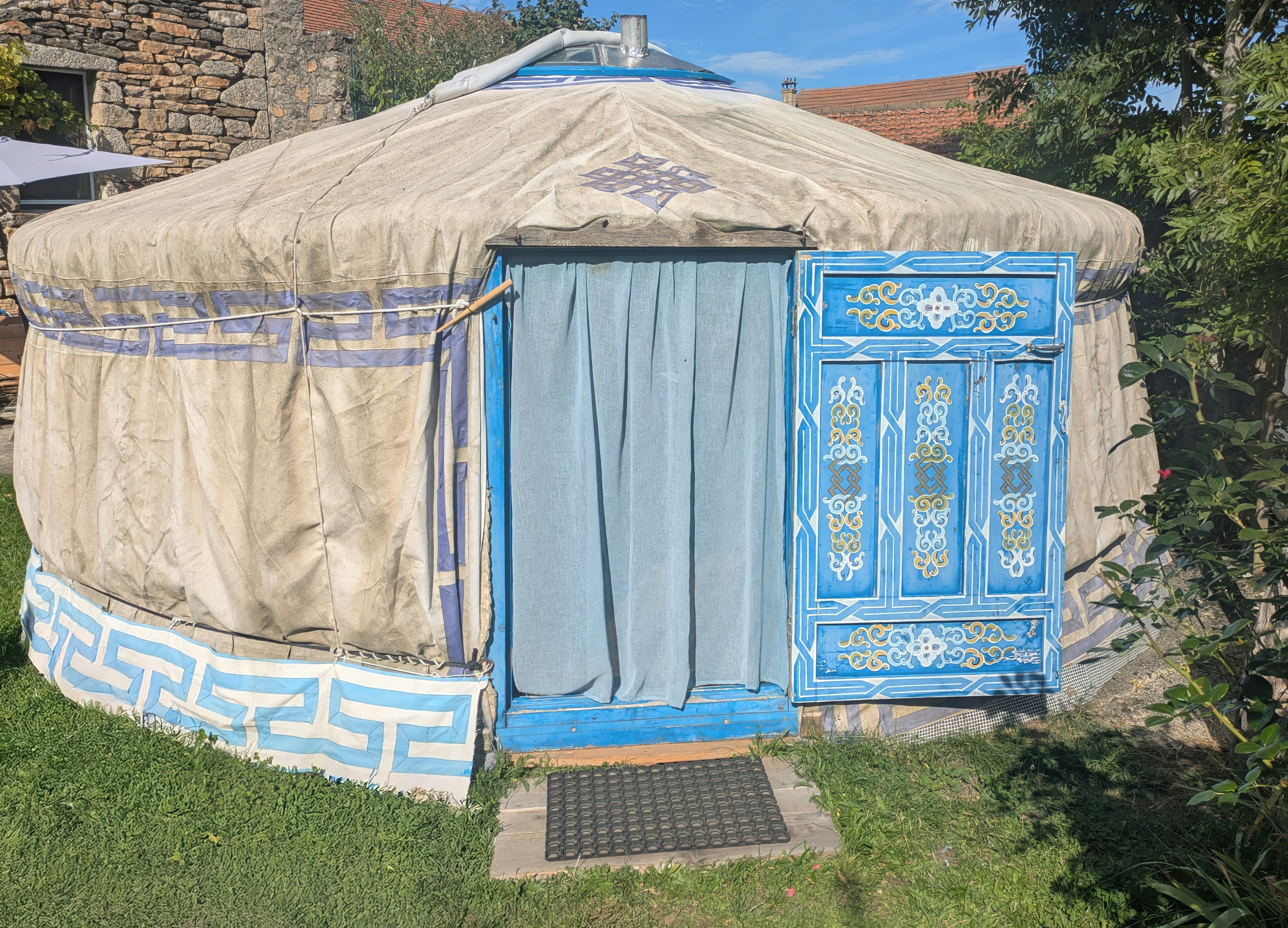A traditional yurt with a blue decorated door and curtains.