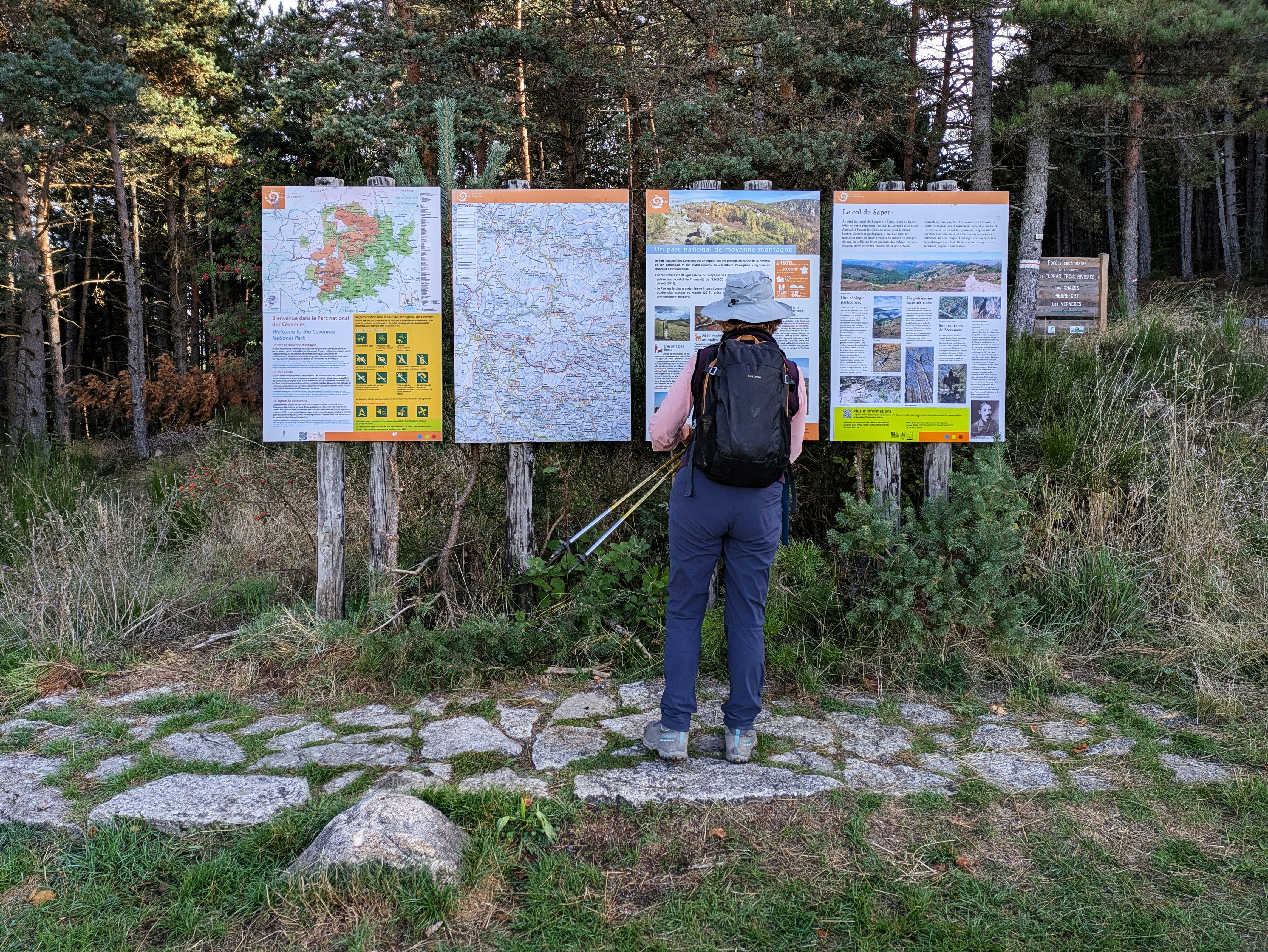 Hiker consults maps at a trail information board.