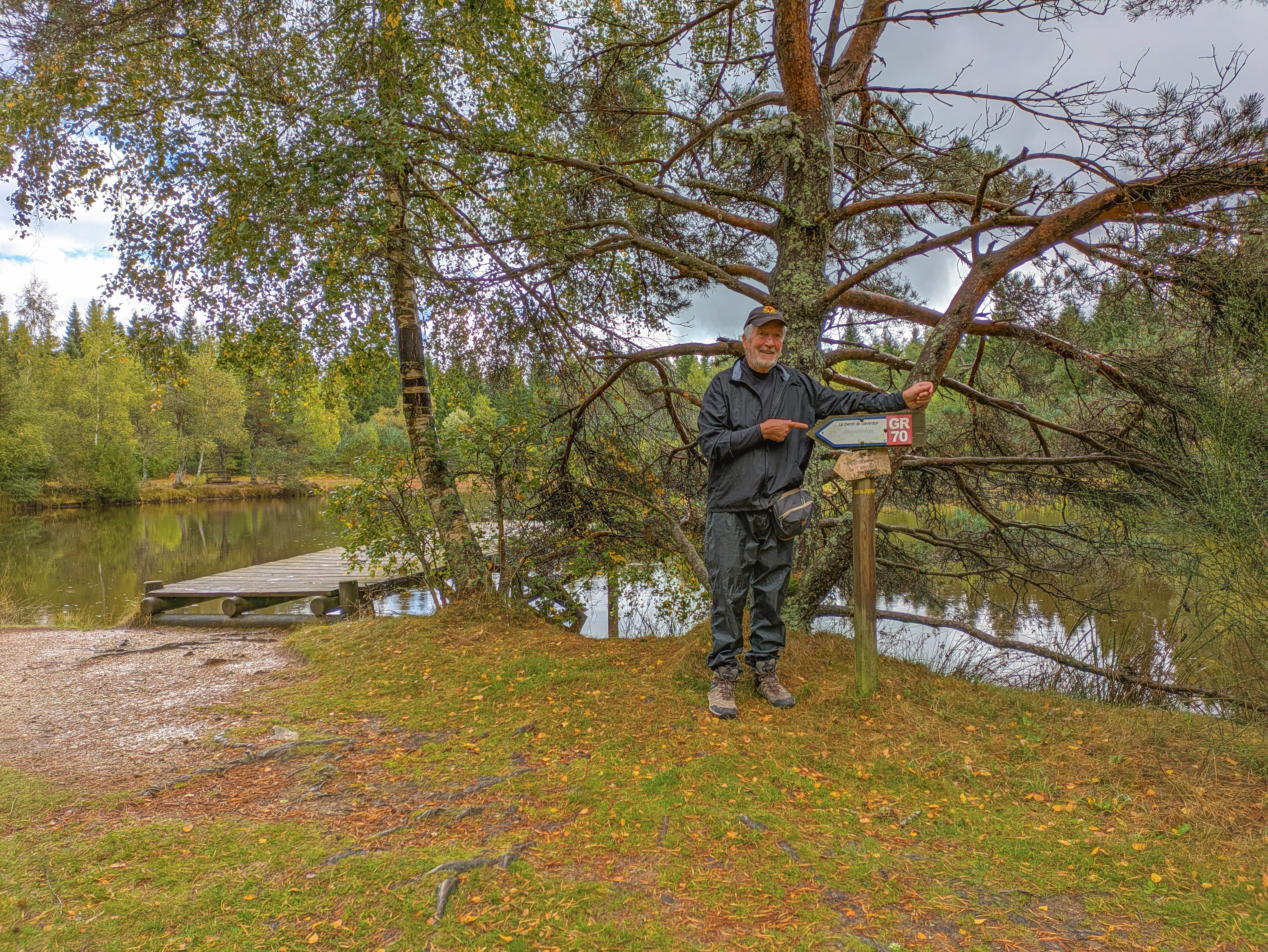 Man standing by a bird feeder near a lake.