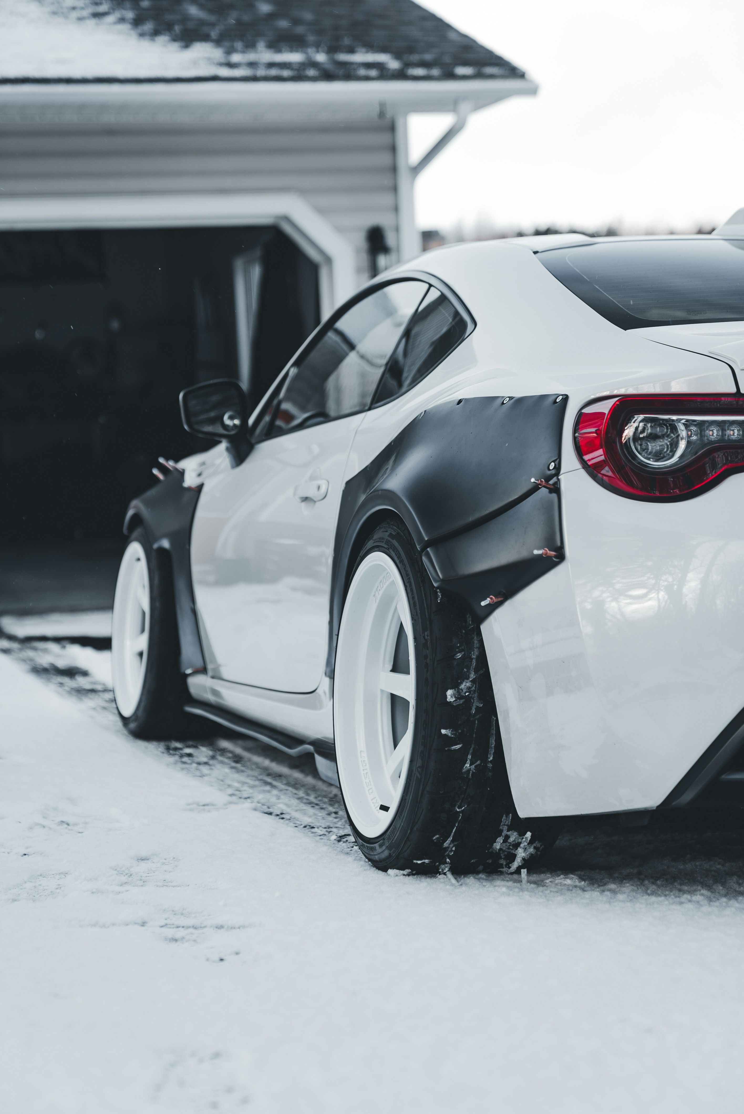 White sports car with widebody kit in snow