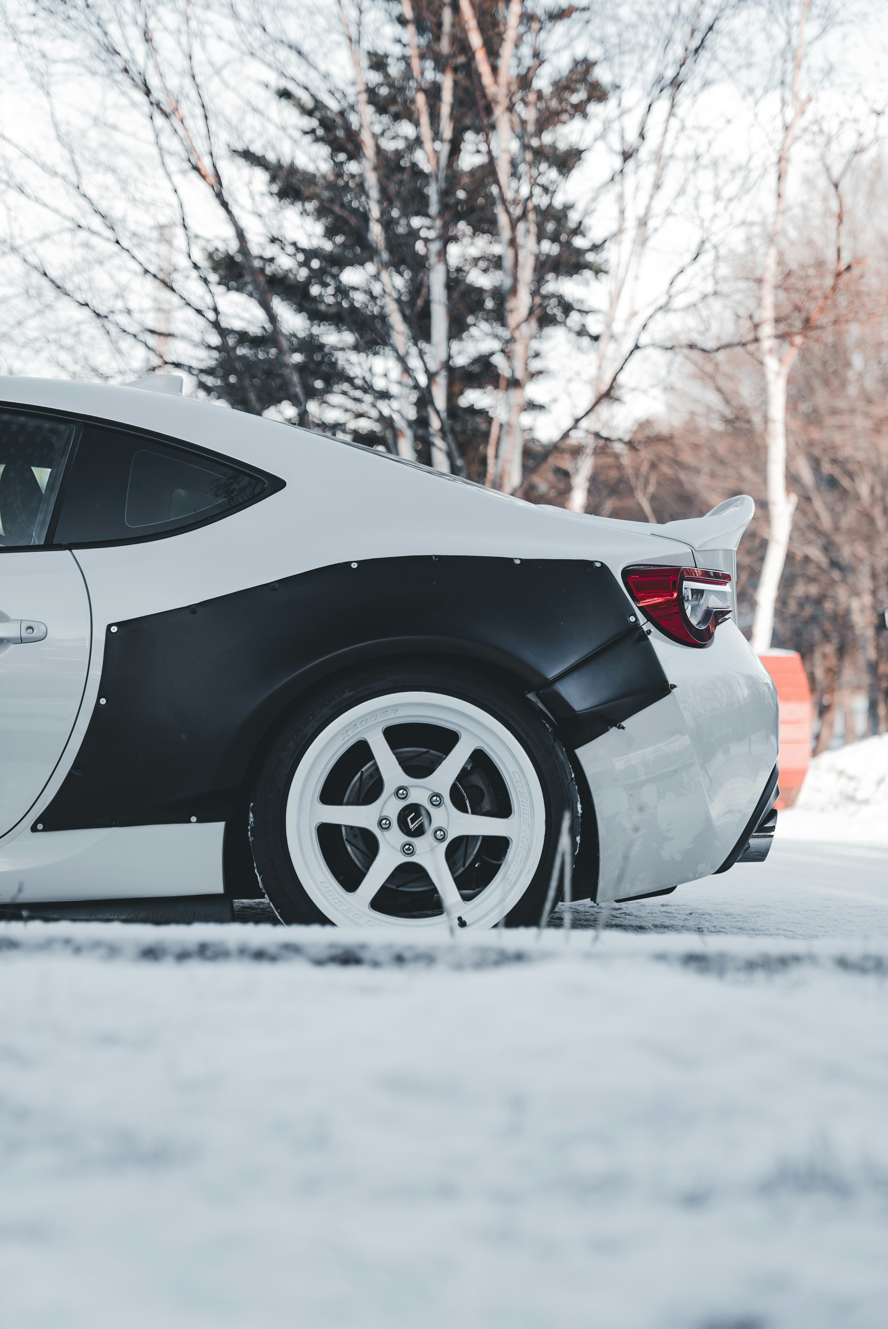 White sports car with widebody kit in snow